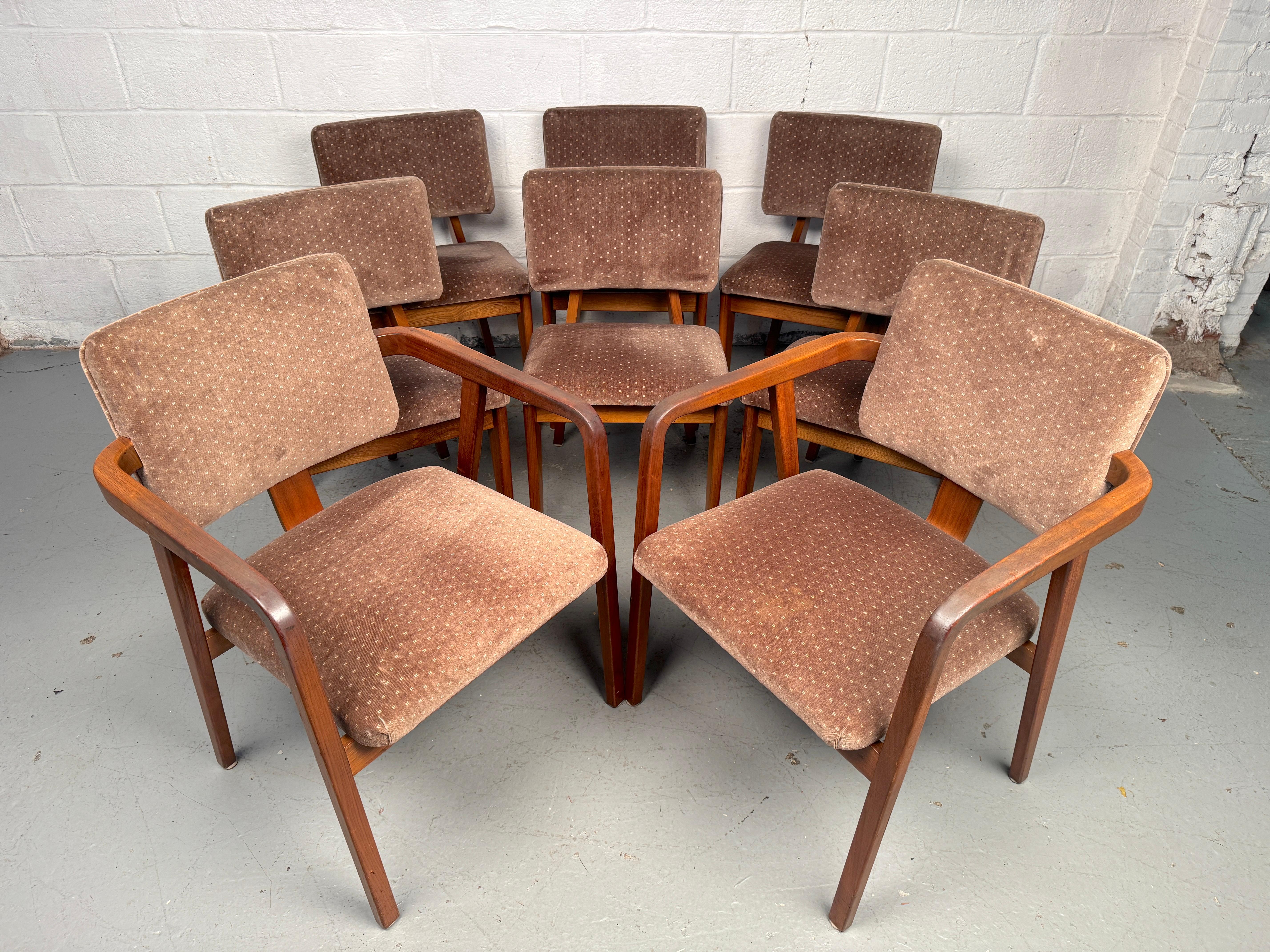 Stylish set of eight mid-century dining chairs featuring cushioned upholstered seats and backs. The set includes two armchairs and six side chairs, all designed with clean modern lines and sturdy construction. This complete set will add both