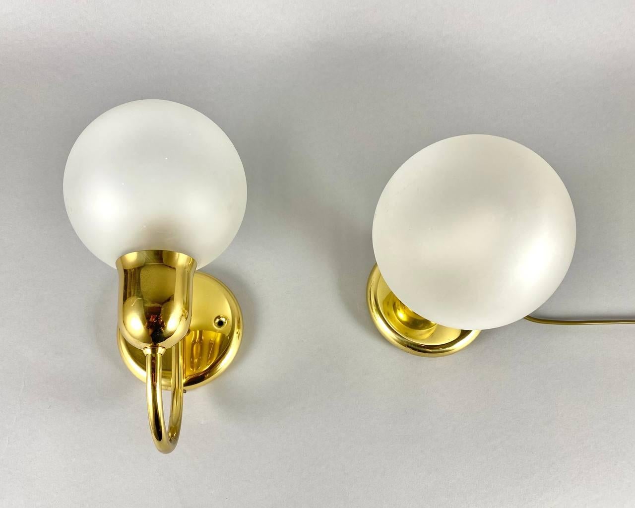 Pair of Art Deco style brass and milk glass sconces.

German vintage lighting.

 A pair of brass sconces and a table lamp with milk glass spherical shades. Each fixture is solid gilt brass.

 Sconce - an artistically executed lamp attached to