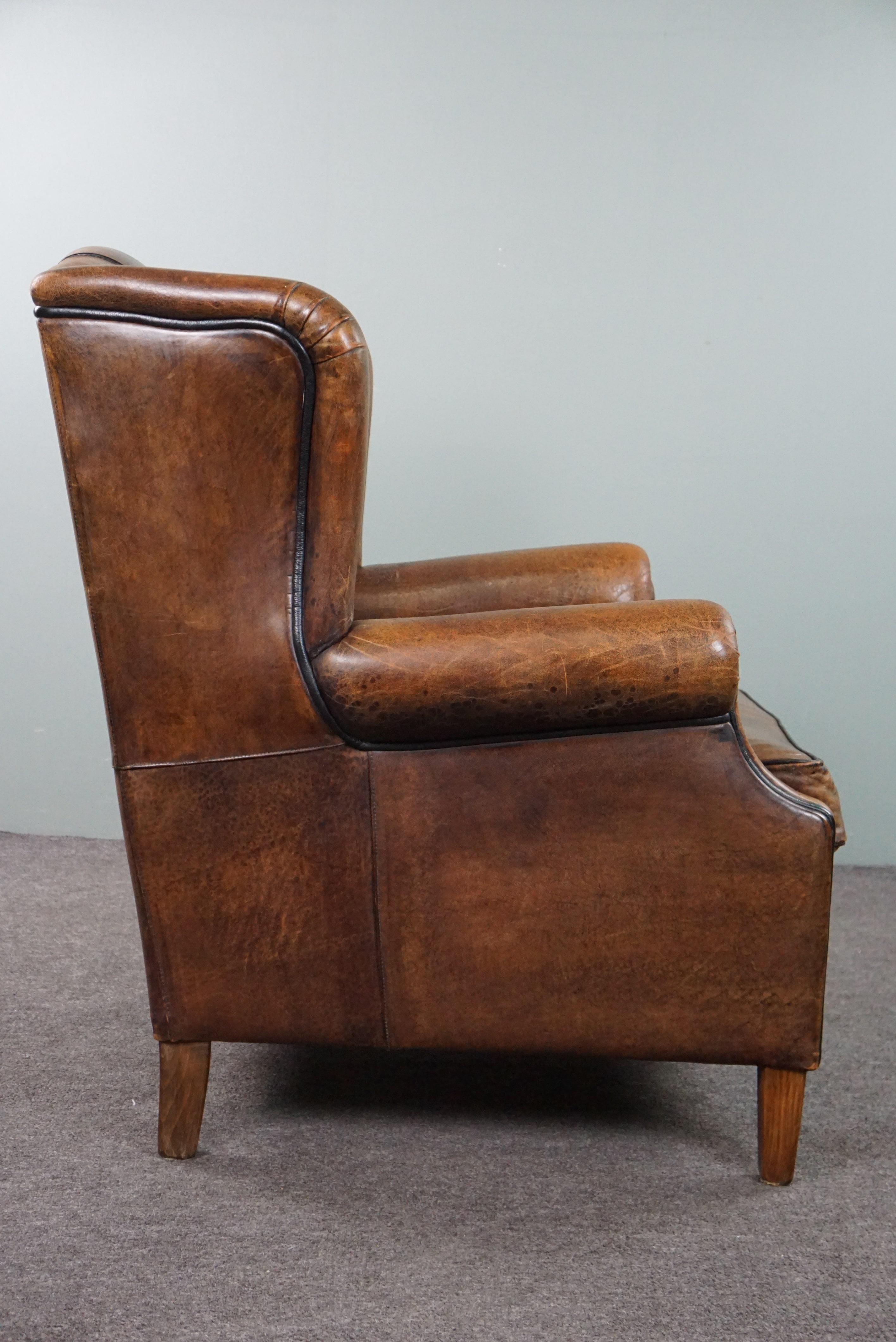 Charming sheepskin wingback chair with black piping and a beautiful patina In Good Condition For Sale In Harderwijk, NL