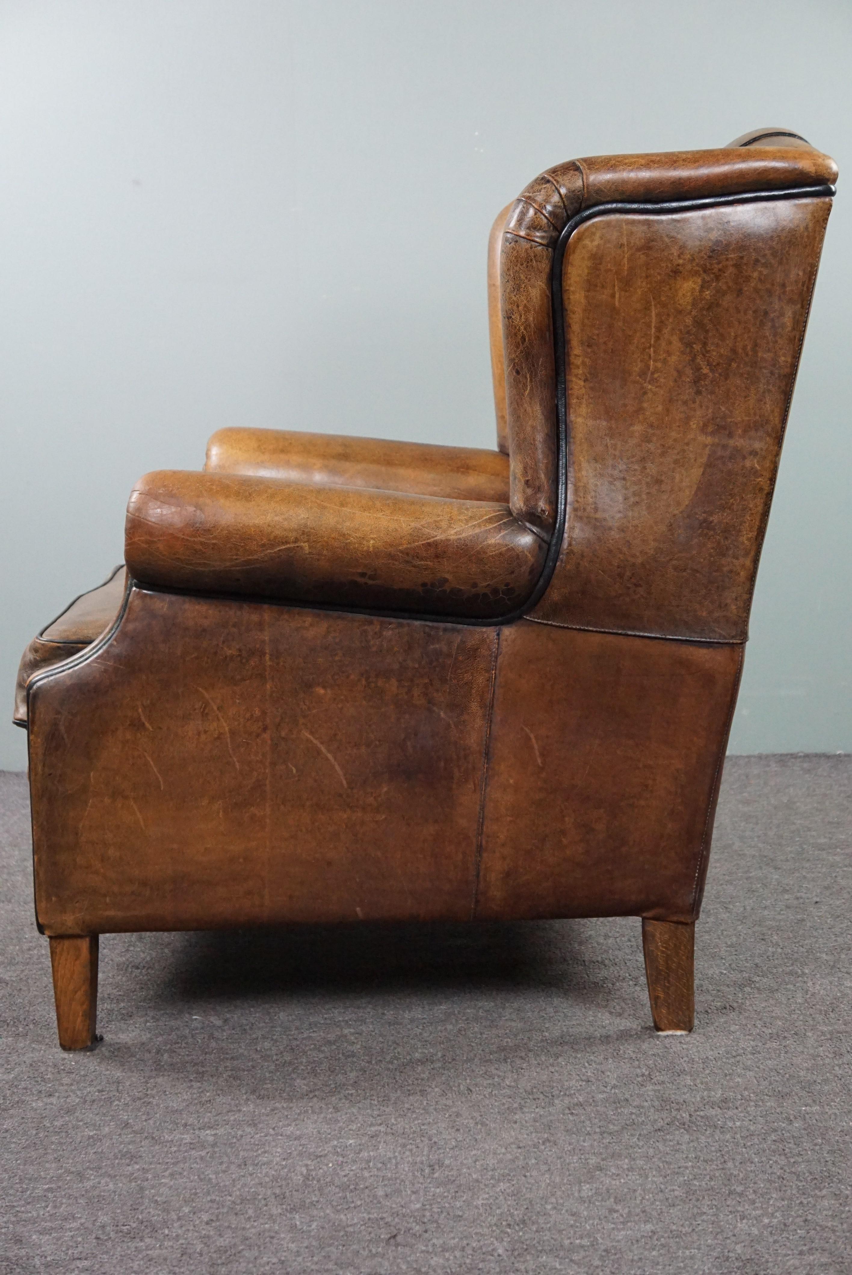 Leather Charming sheepskin wingback chair with black piping and a beautiful patina For Sale