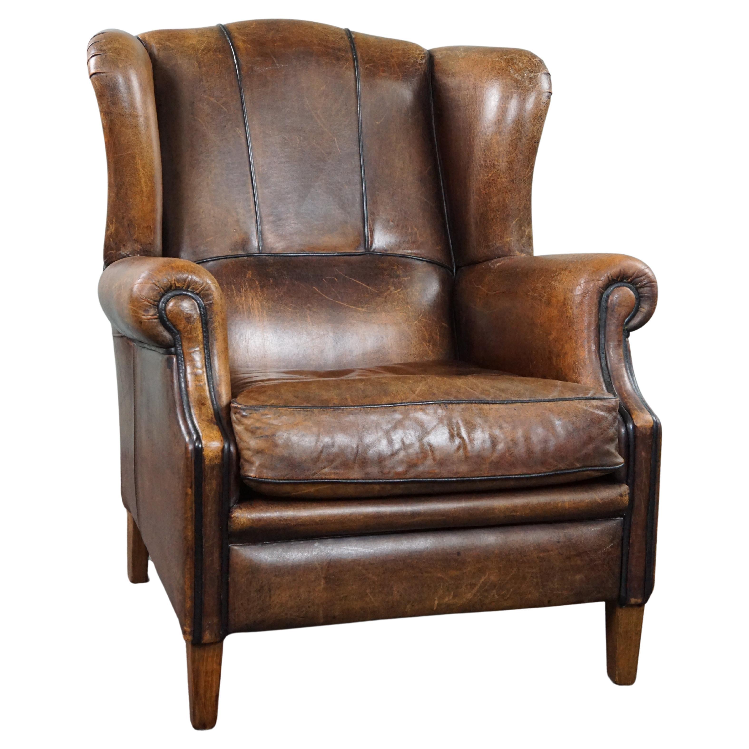 Charming sheepskin wingback chair with black piping and a beautiful patina For Sale