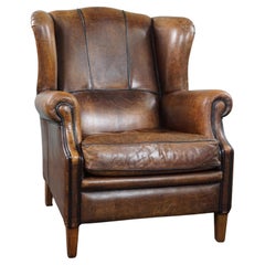 Charming sheepskin wingback chair with black piping and a beautiful patina