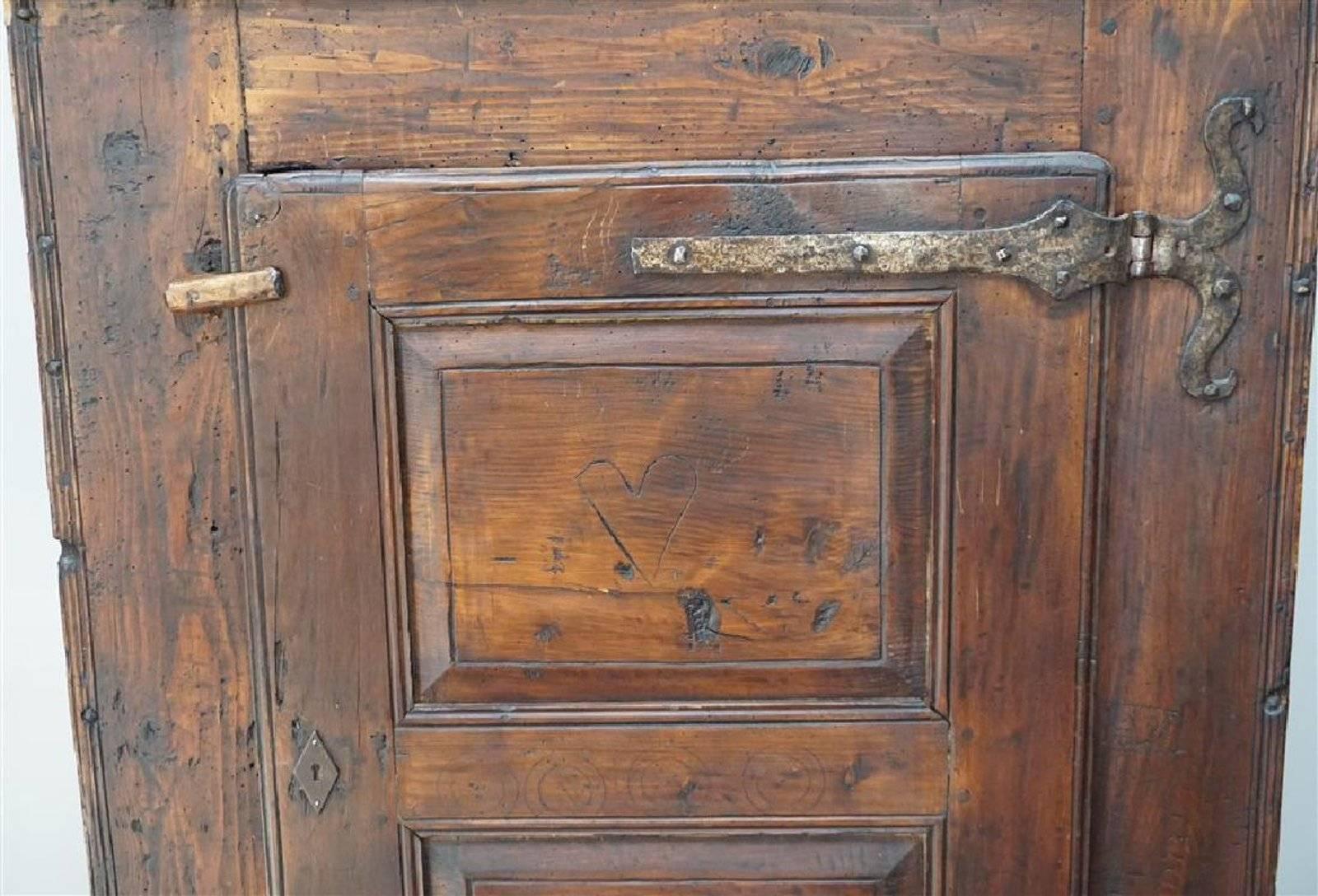 Charming small 18th century French provincial rustic cupboard made of pine and poplar with a deep patination and rich lustrous color. Made in the Dordogne region with a single paneled door retaining the original scrolled strap hinges. Good small