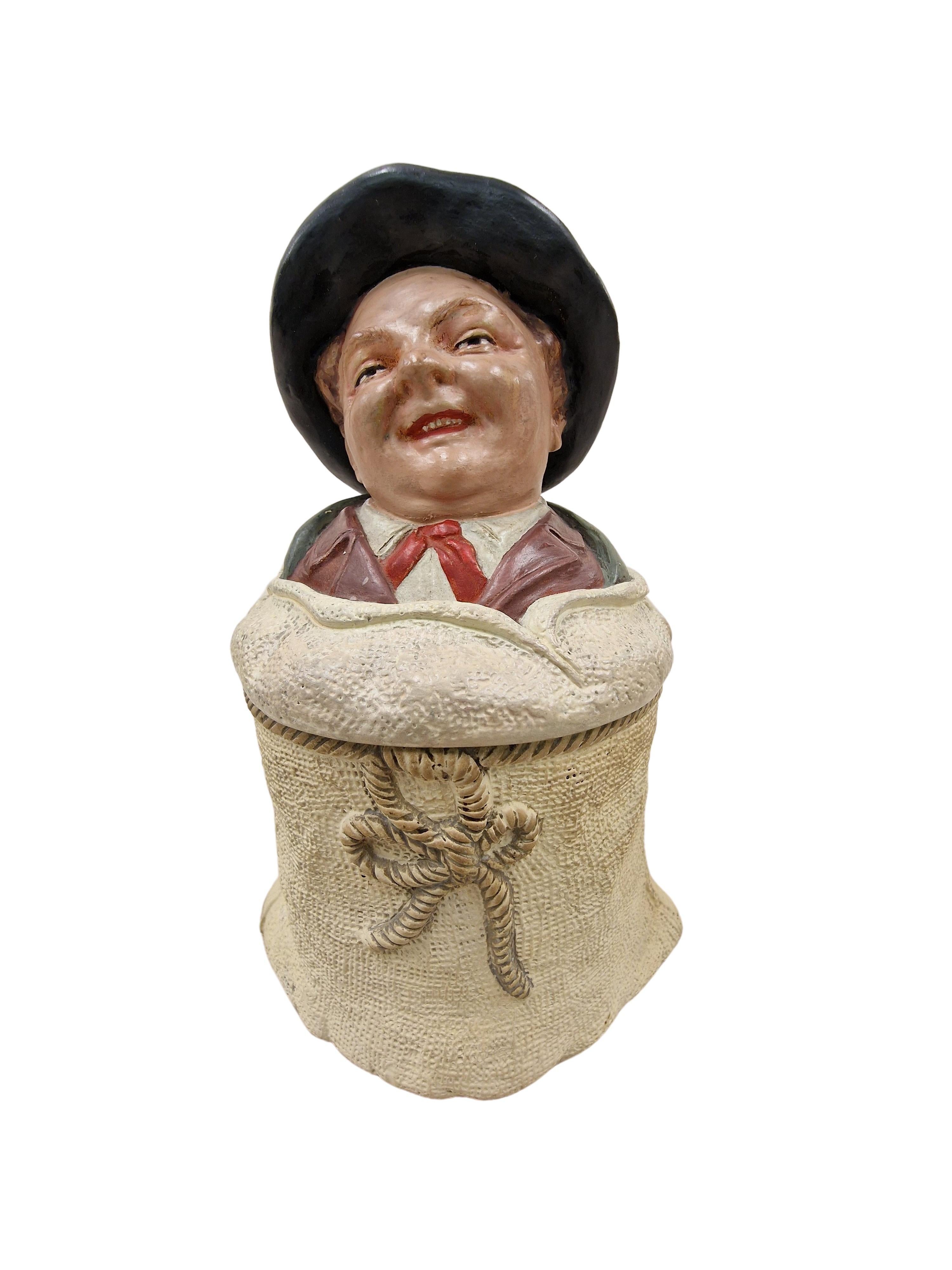 Extraordinary, charming tobacco box, made in the 1910s, an original art nouveau piece, made by wellknown Johann Maresch, Czech Republic. 

The tobacco tin is designed like a linen bag, tied with a rope. Above - on the lid, is a laughing man, it