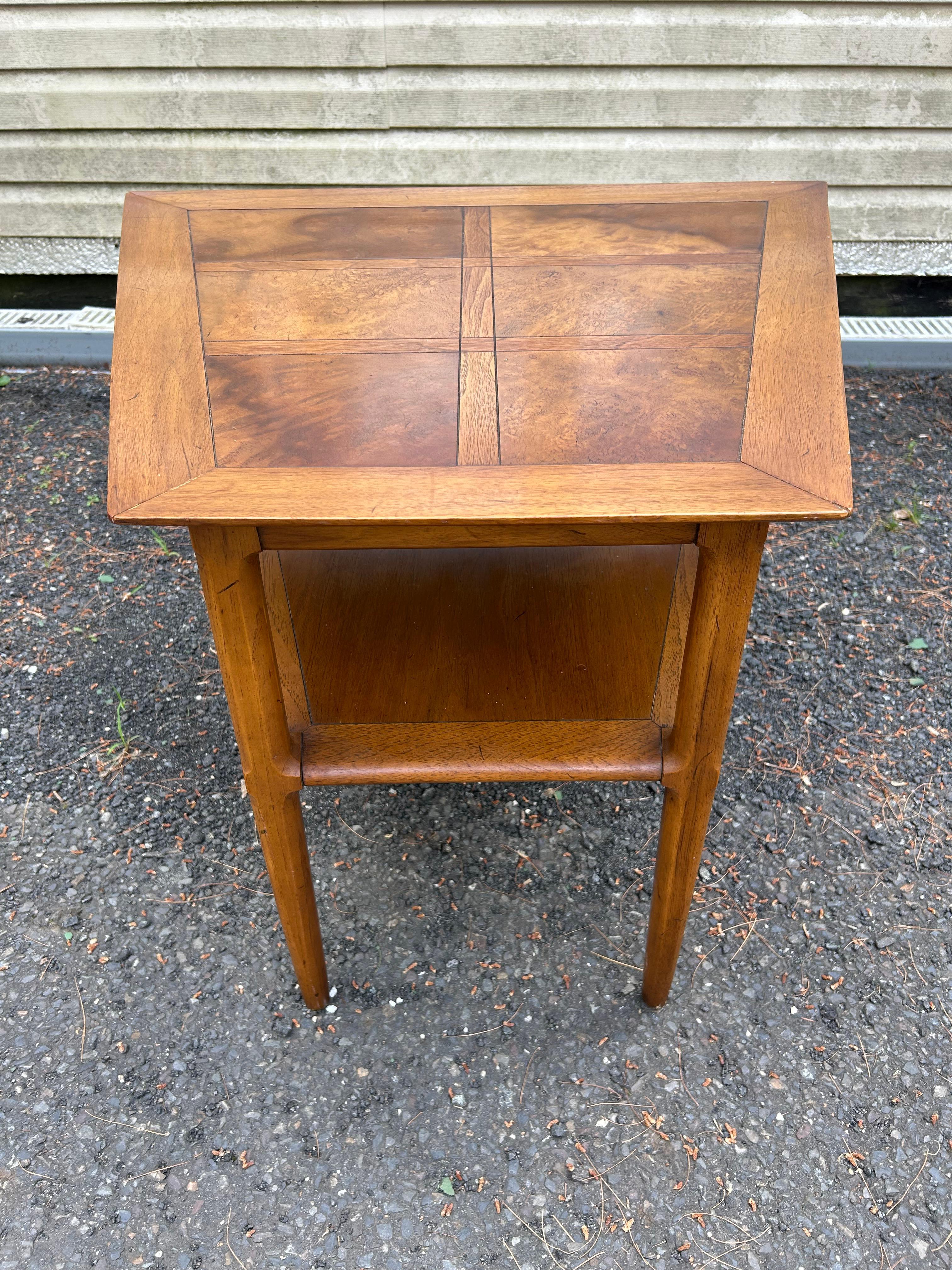 Charming Tomlinson Sophisticate trapezoid shaped end table. This mid century modern wedge table from the Sophisticate series by Tomlinson features two tiers, the top tier bearing eye-catching contrasting burl-wood panels that add an element of depth