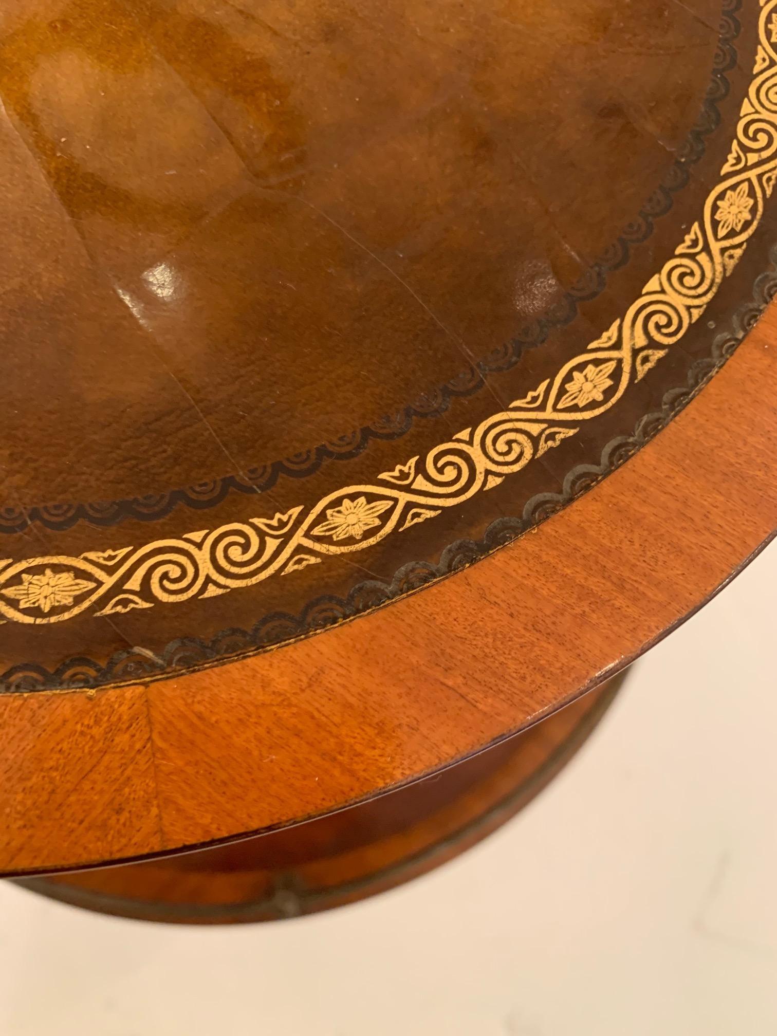 Unusual very functional two-tier round mahogany side or drinks table having handsome tooled leather surfaces, twisted brass round top handle, brass gallery and feet.