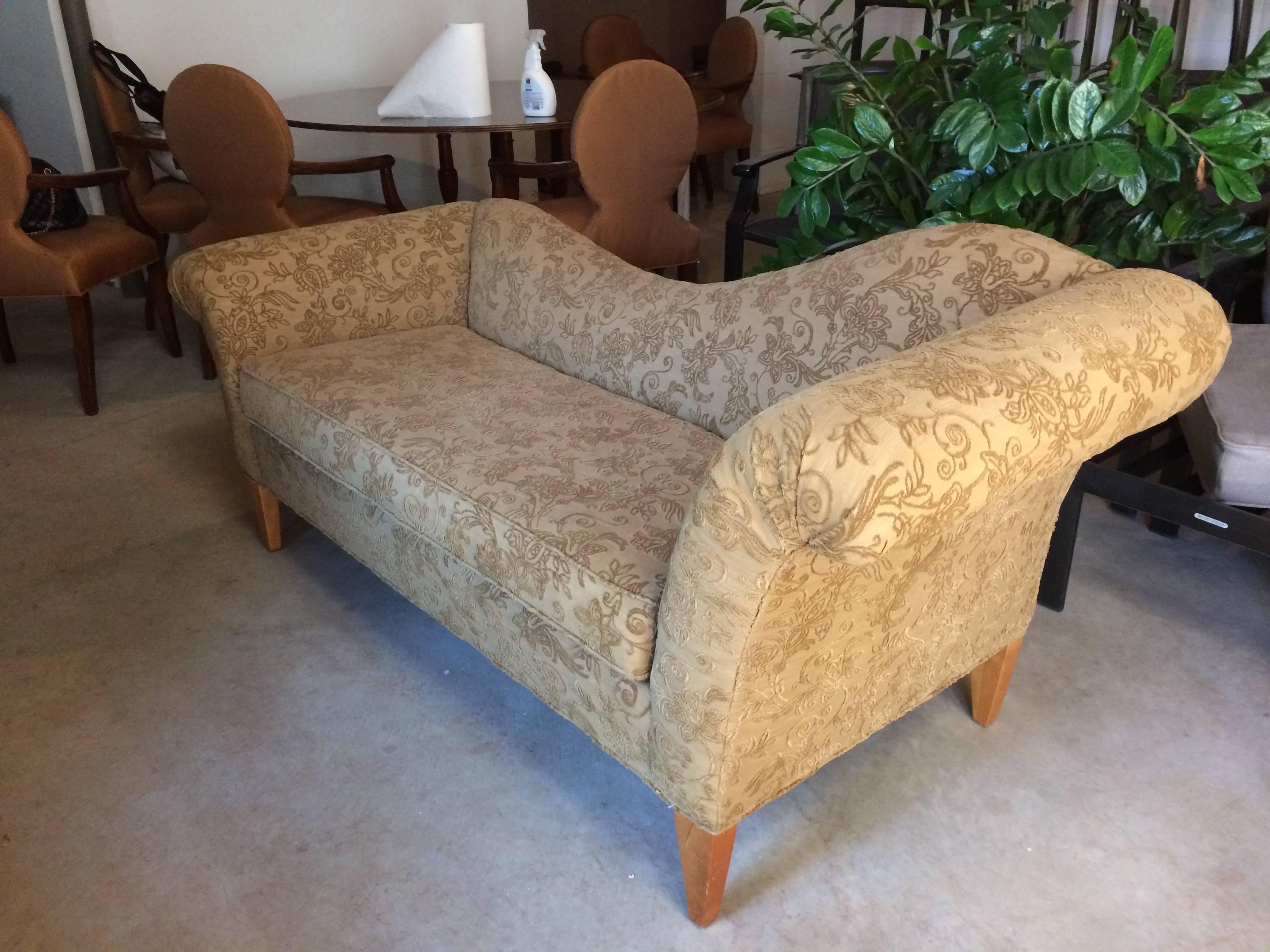 Romantic upholstered sofa with one side higher than the other with elegant sexy Silhouette, having a raised chenille type of fabric in a versatile brownish green. Tapered light wooden legs. Measures: Seat height 19.5, seat depth 20.