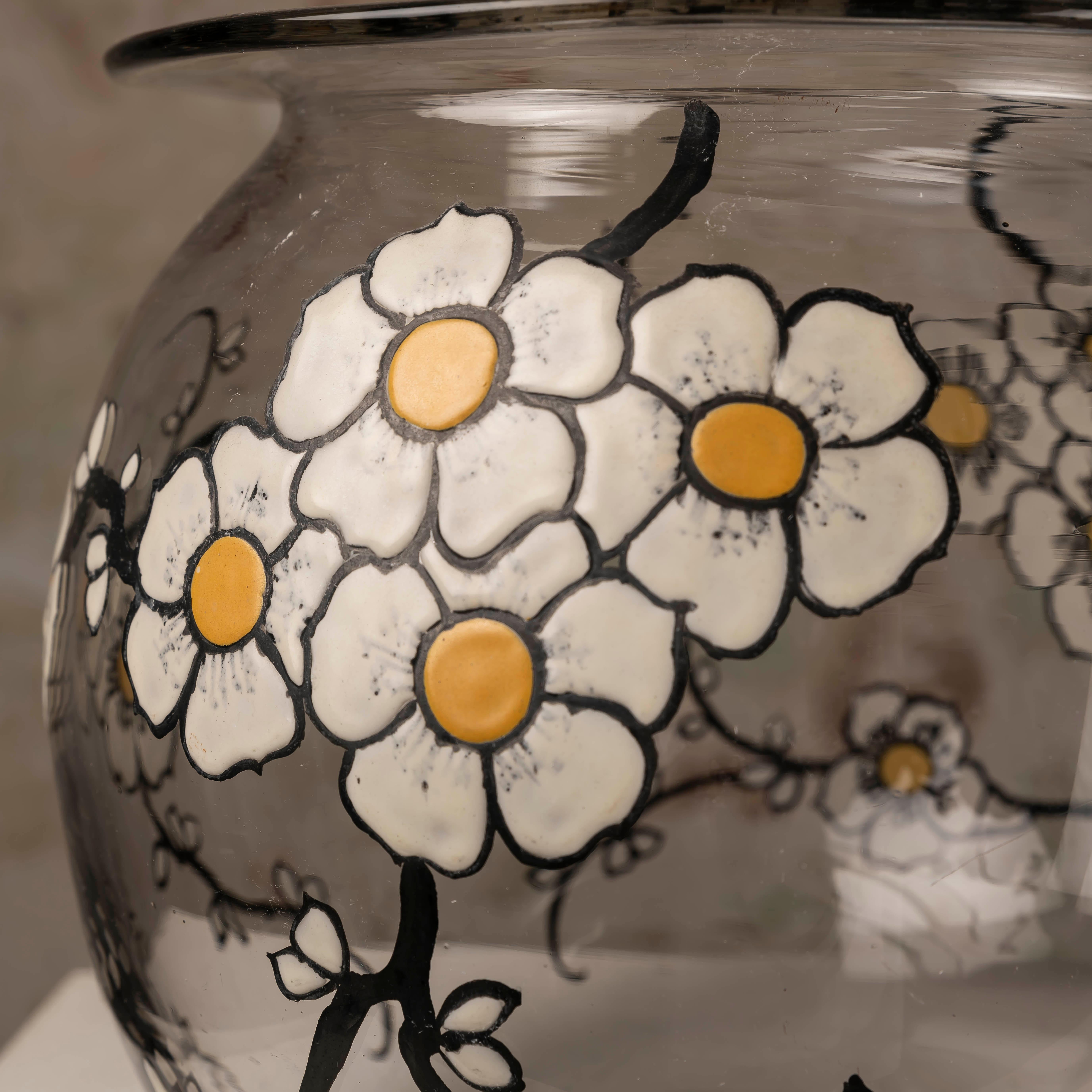 Diese bezaubernde Vintage-Glasvase mit Emailleblumen ist mehr als nur ein dekoratives Stück - sie ist ein Zeugnis zeitloser Schönheit und Handwerkskunst, das jeden Raum aufwertet. Die zarten Emailleblumen, die von Hand auf die Glasoberfläche gemalt