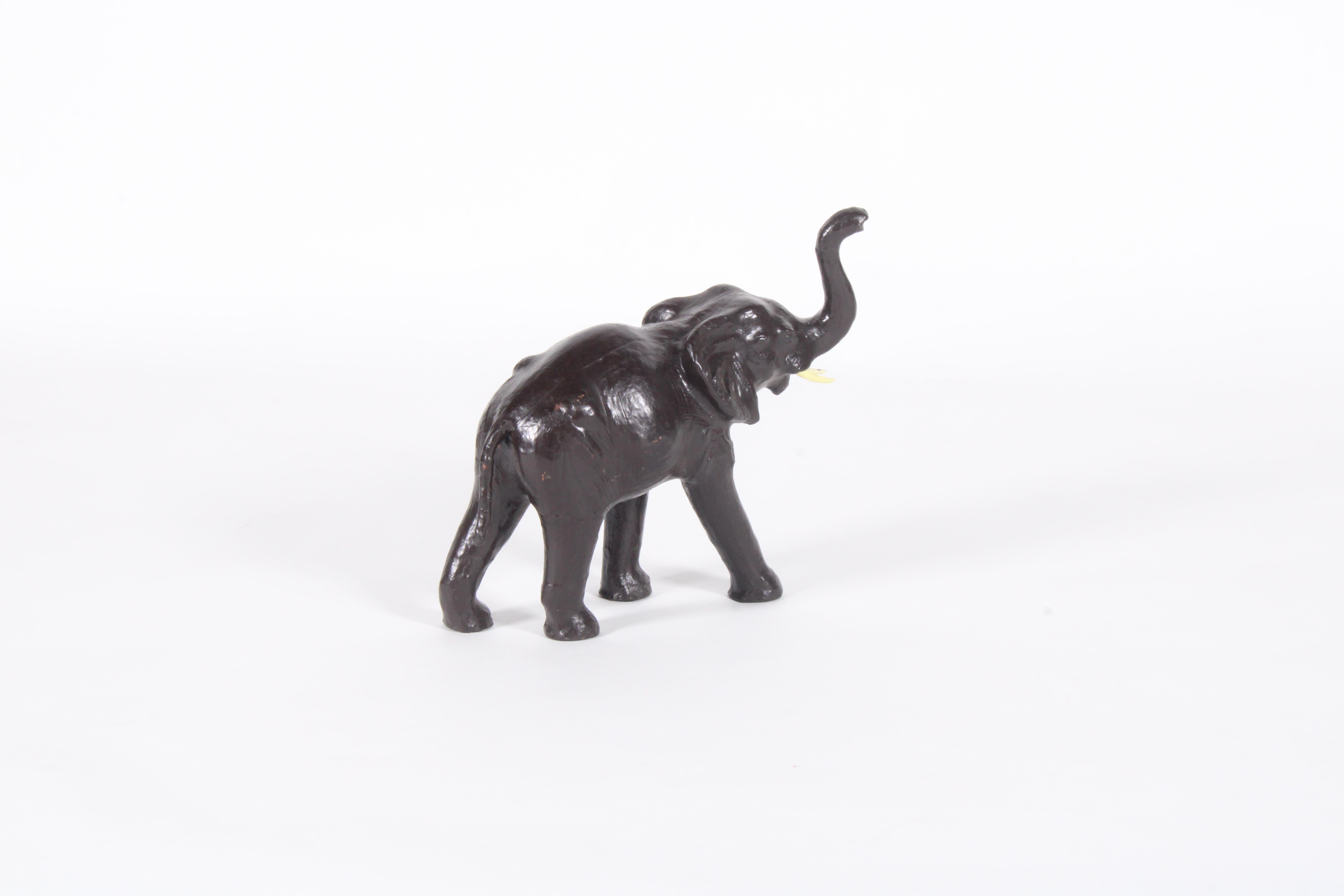 Un'affascinante scultura vintage di un elefante, splendidamente realizzata in pelle marrone e invecchiata alla perfezione con la patina più desiderabile. Le zanne sono state realizzate in materiale plastico e si posizionano perfettamente. Questa