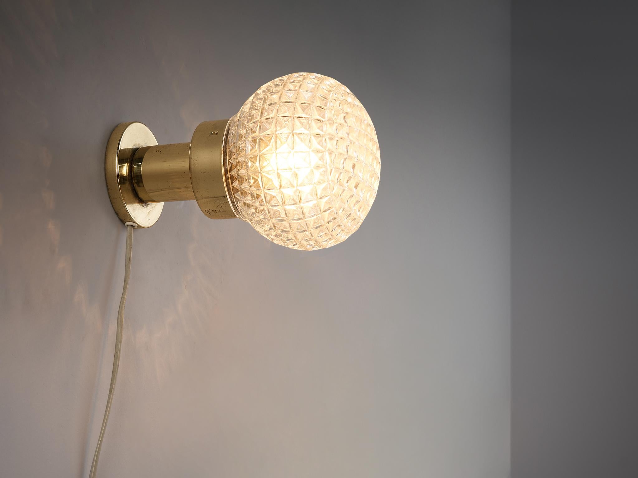 Wall light, glass, brass, metal, Czech Republic, 1960s.

This eccentric wall light is made in the 1960s in the Czech Republic. This design is based on a round construction. The structured glass orb with an ocher tone is supported by a round shaped