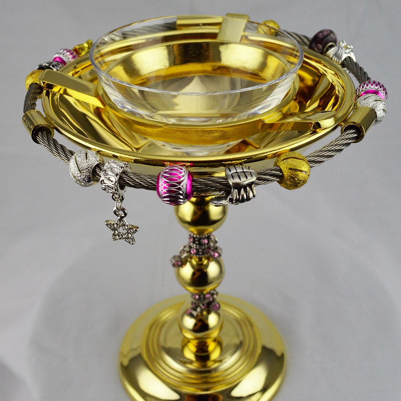 Sumptuous and elegant, this caviar bowl will add a special accent to a lavish dinner. Its dynamic silhouette is made of gold-finished metal with the addition of a series of charms on the stem and around the rim that add a playful accent to the