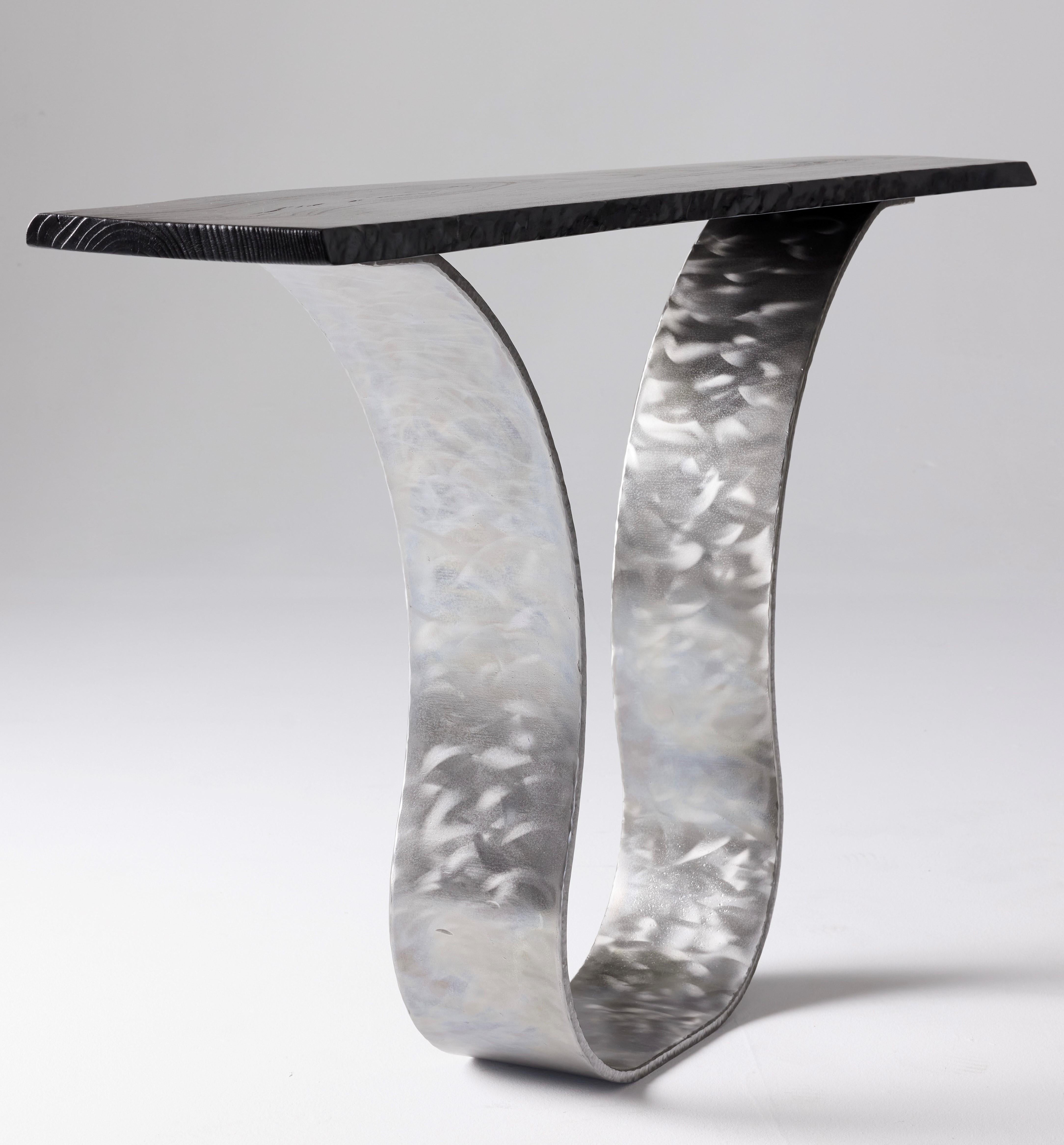 This elegant console table by Carlo Stenta is a sculptural entry table that combines modern-industrial with the organic. Recovery Furniture’s Tina Console in polished steel features a charred live edge slab of maple resting upon a solid steel base.
