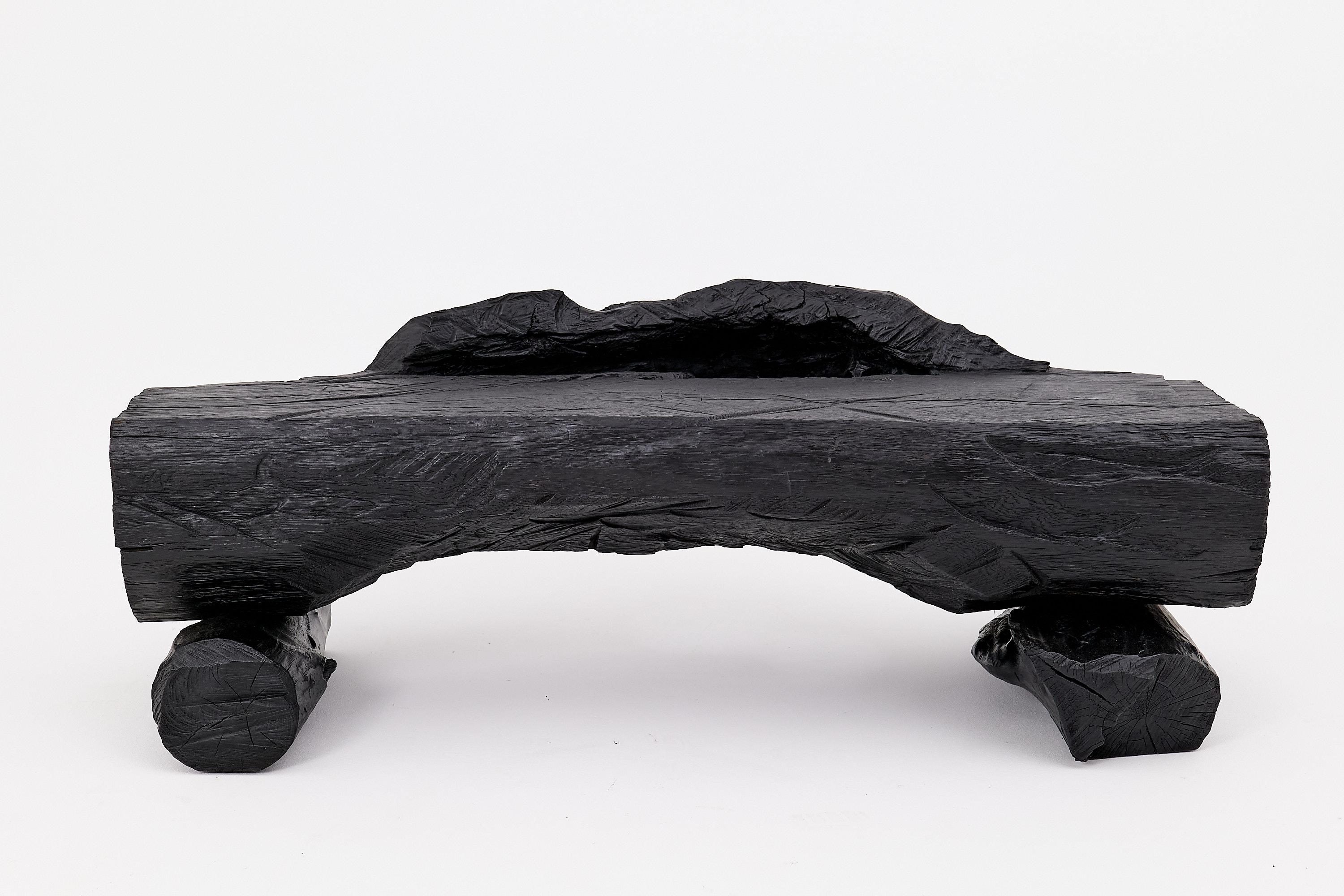 Diese skulpturale Bank ist ein einzigartiges funktionales Kunstwerk, das mit der Kettensäge aus einem Stück Holz geschnitzt wurde.  aus massivem Hartholz und verkohlt nach der alten japanischen Shou Sugi Ban-Technik. Seine rohe, gewölbte Silhouette