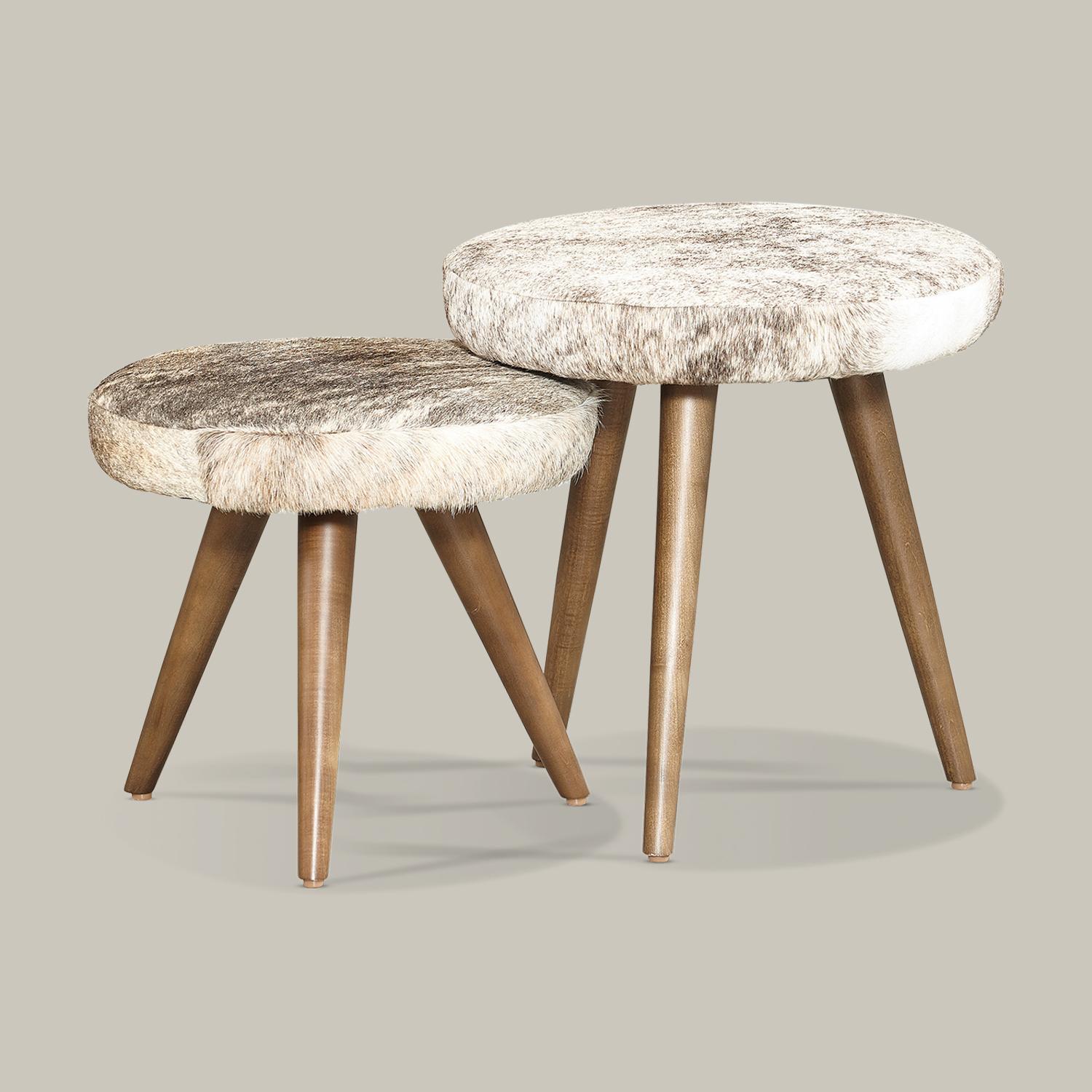 Upholstered stool in natural hair-on-hide leather with 3 tapered legs in solid hardwood forms a unique, functional accent reminiscent of global design traditions. Each piece is one-of-a-kind due to subtle, natural variations in the premium hair on