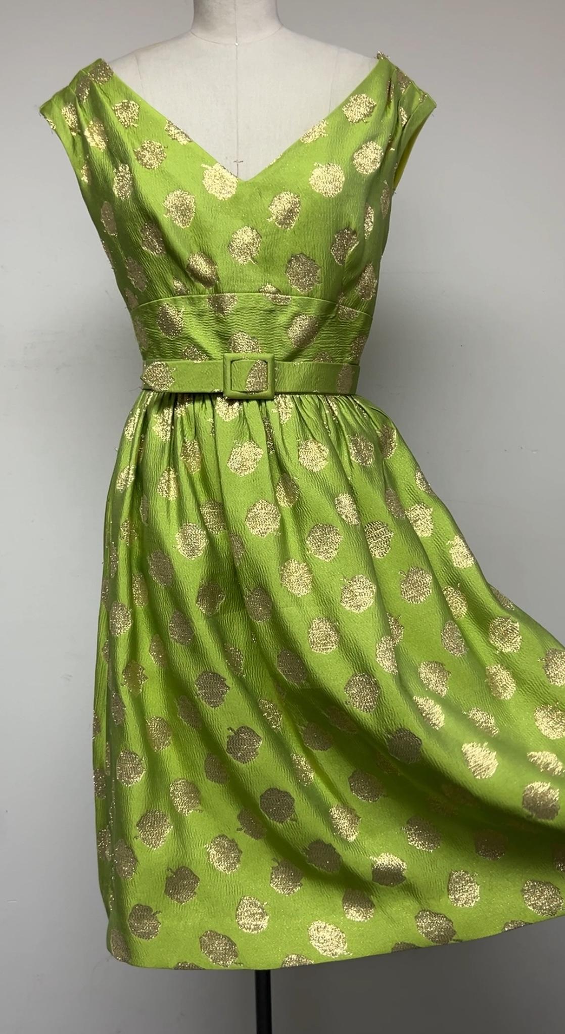 Vestido de fiesta divertido y festivo. Este vestido está confeccionado con un tejido único, un brocado de lunares chartreuse y dorados de origen inglés. La silueta presenta un escote en V con pliegues en los hombros y falda ajustada. Inserto en la