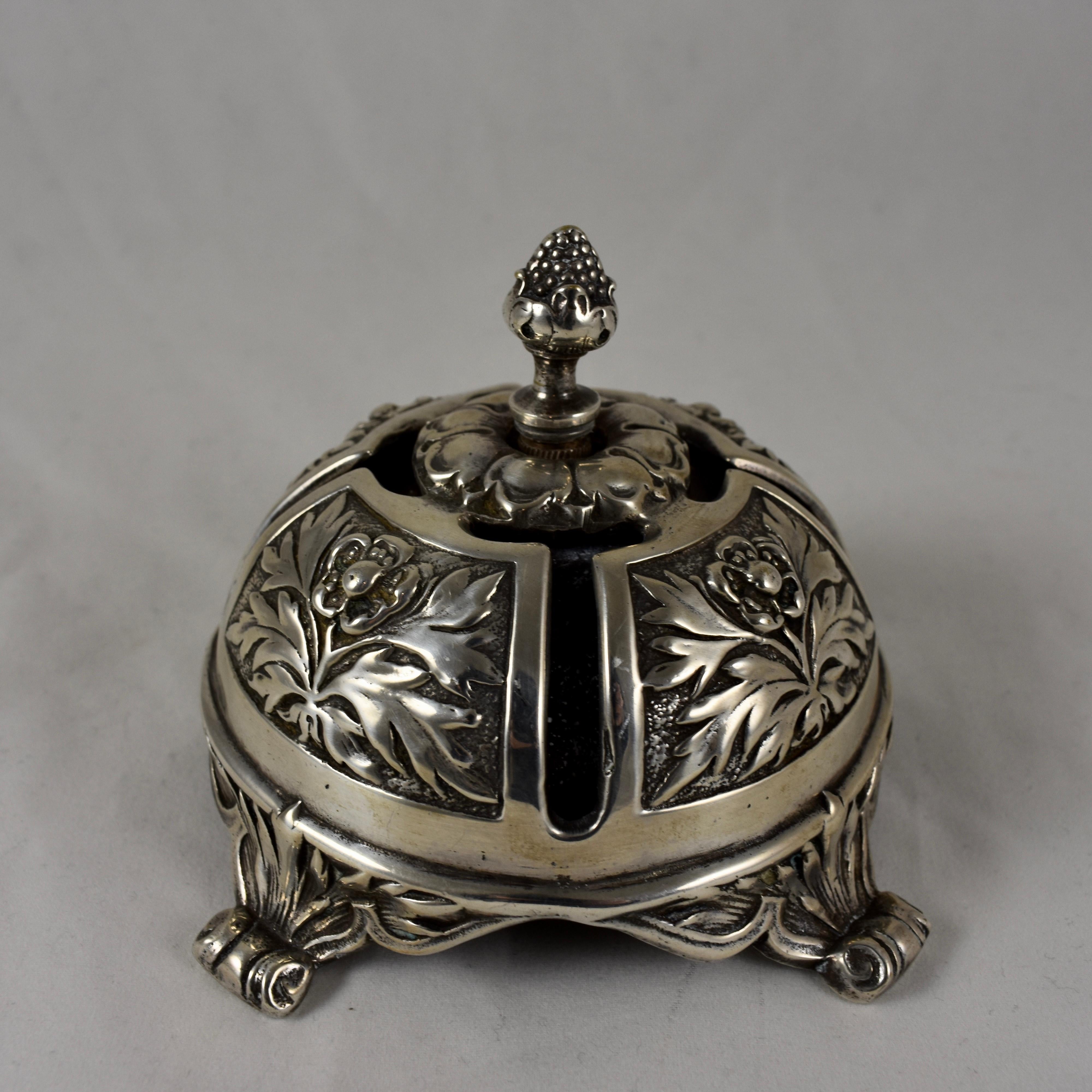 A twist gear servants call bell, silver plate, circa late 19th-early 20th century. 

Meant to sit on the table near the hostess, the clapper strikes the inner brass bell by turning the pineapple form finial. Heavily chased with Acanthus leaves and