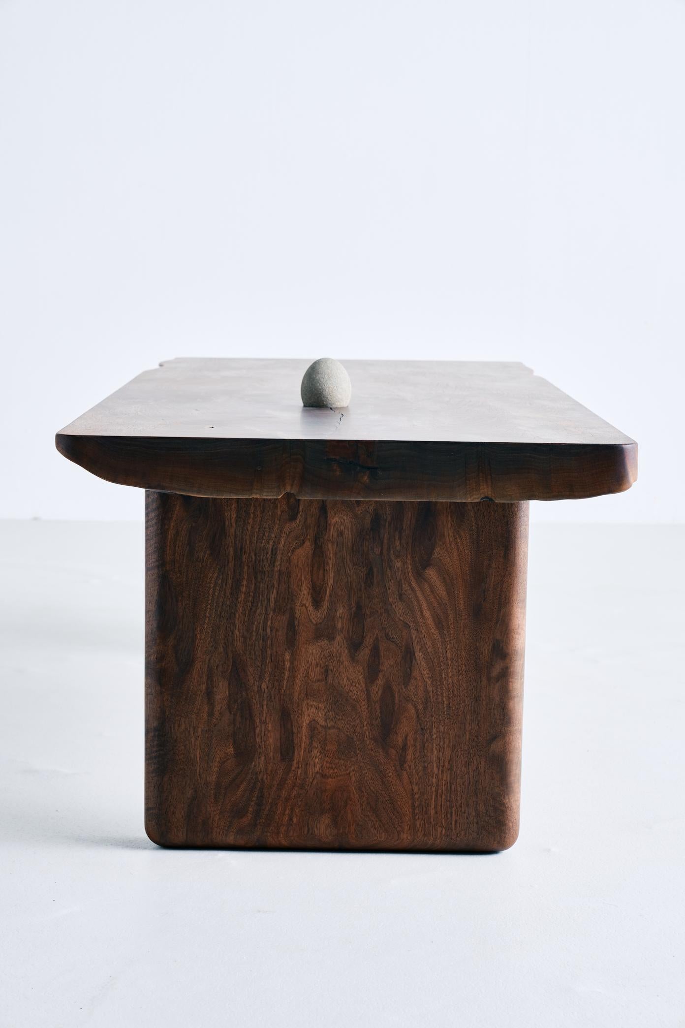 The Chasm coffee table by Brian Grasela was built from a single slab of Oregon black walnut. A beach stone found in San Diego, California is incorporated into the top along with a casted bronze burl inlay on the underside of the table. The table is