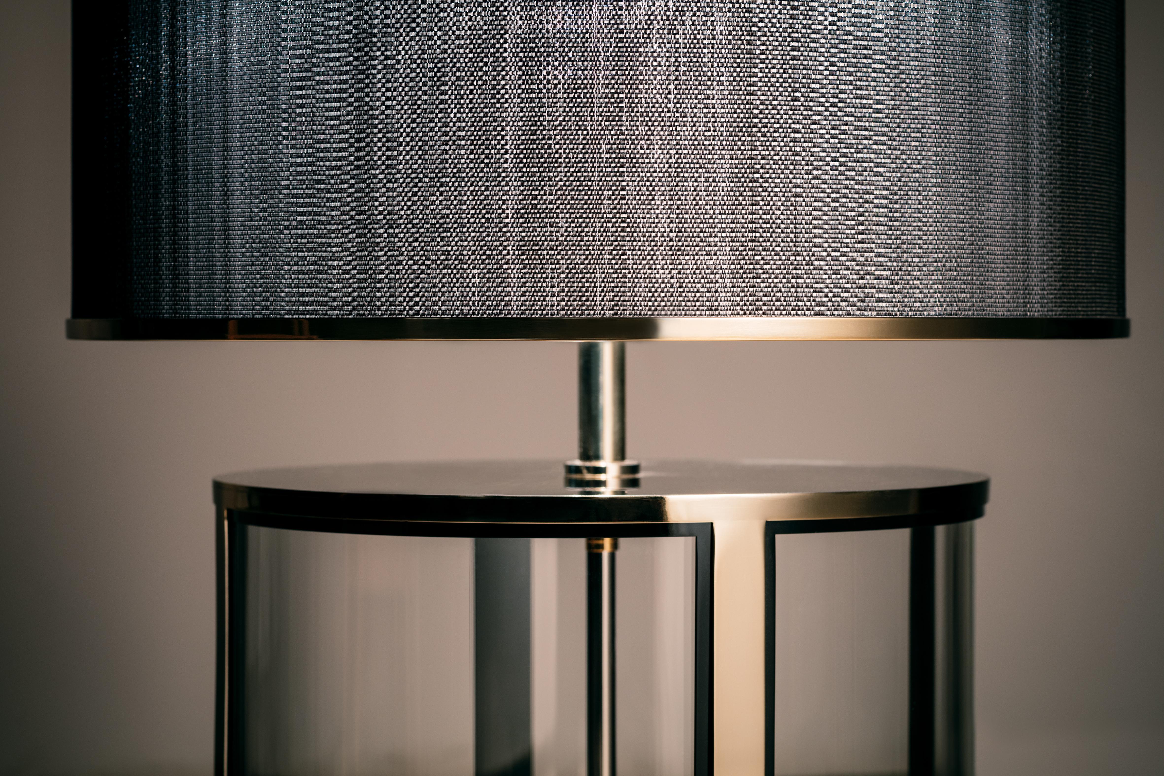 A table lamp of generous proportion yet seamless transparency. The interior is exposed to allow visibility through the base of the lamp. The curved glass acts as a lens, slightly distorting the moving landscape beyond. There is a strong contrast