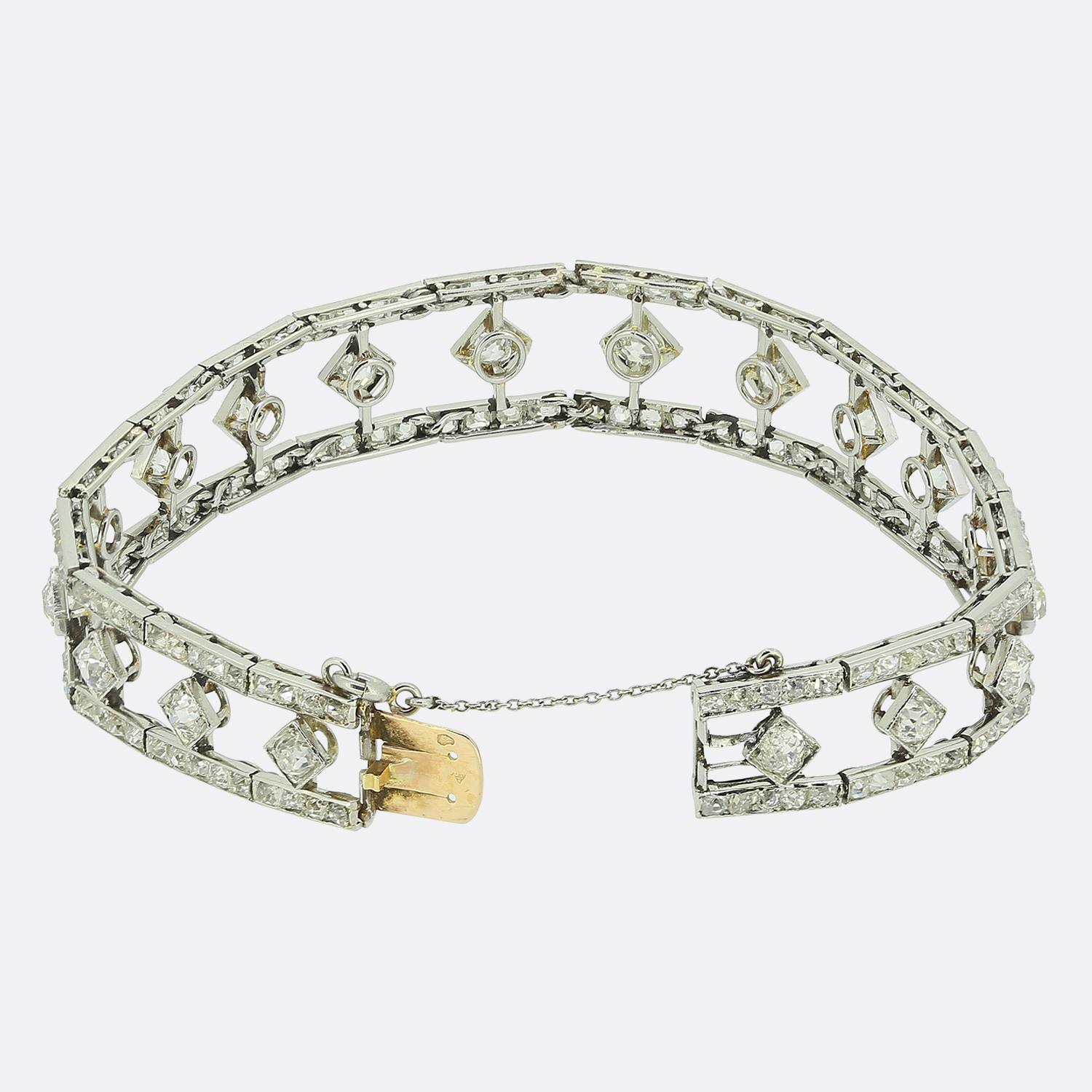 Aquí tenemos una exquisita pulsera de platino y oro de 18 quilates de Chaumet. Esta pieza de la Belle Époque de 1910 presenta un delicado diseño calado, adornado con gruesos diamantes talla mina antigua en el centro; cada uno de ellos ha sido