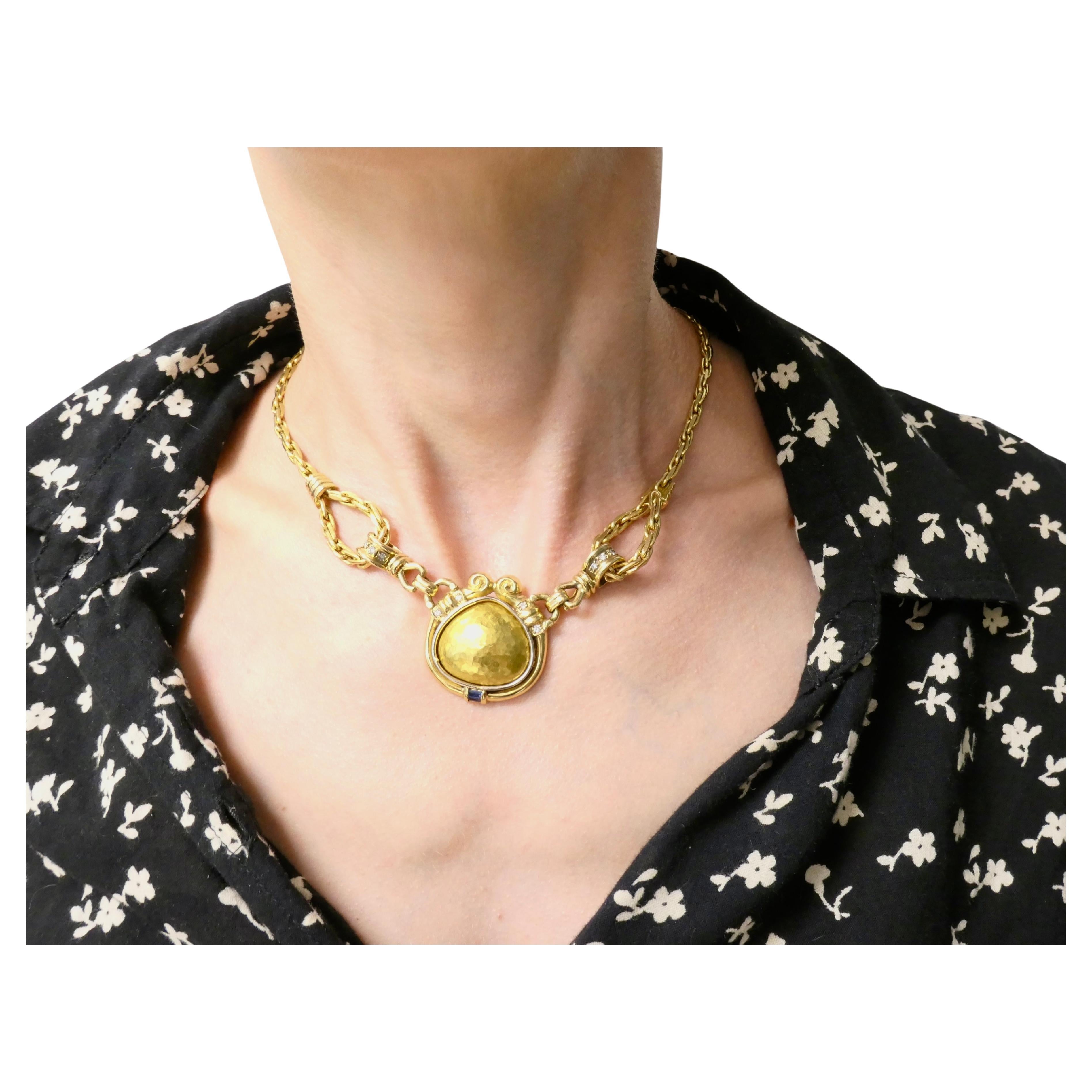 A gorgeous Chaumet necklace crafted in 18k gold, featuring diamonds and sapphire.  This Chaumet necklace features a tear-drop shaped pendant, elegantly suspended from two links that connect it to a finely woven gold chain. The latter includes two
