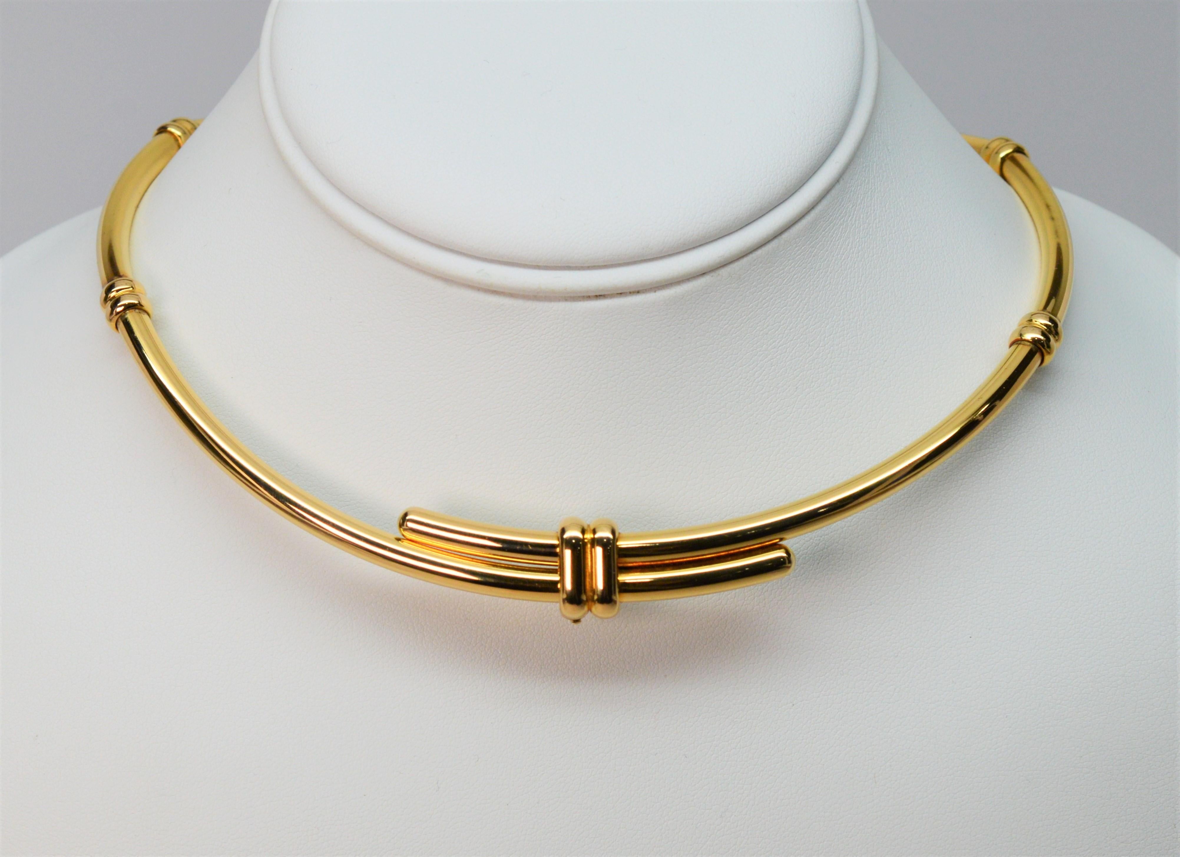 A contemporary crossover knot is the focal point and acts as a hidden clasp on this sleek necklace design by Chaumet of Paris. Made of polished eighteen karat 18k yellow gold, this choker style necklace is engineered with precisely matched hinged