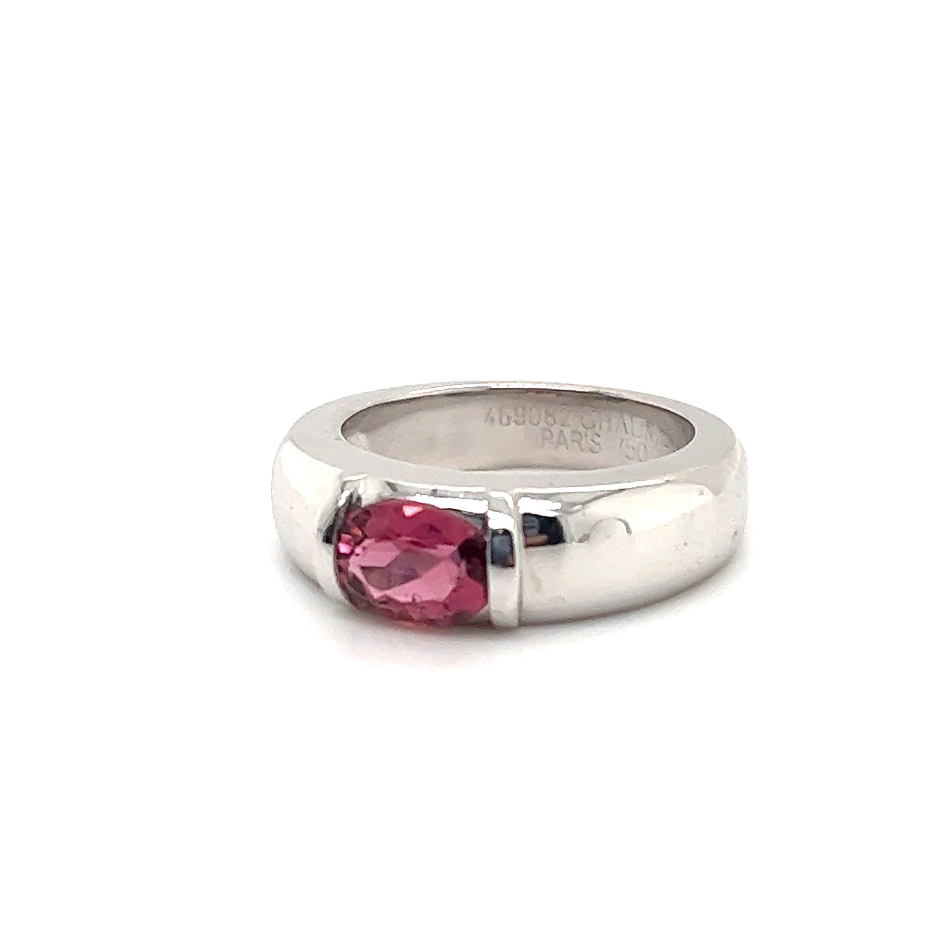 Gorgeous minimalist ring by famed jewelry house Chaumet. This simple, yet elegant design is crafted in 18k white gold. The ring shows a simple band design that shows a raised lip in the center where a oval  cut pink tourmaline is set east/west in