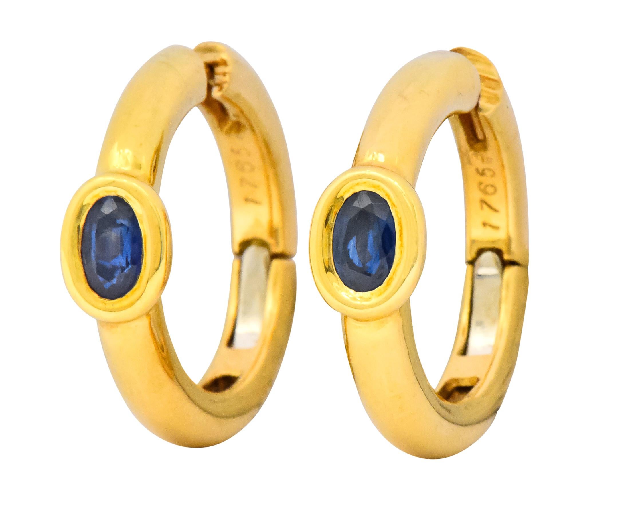 Hoop style earrings, each centering an oval cut sapphire, total sapphire weight approximately 1.00 carat, bright deep blue and very well matched 

Sapphires are bezel set in the high polished gold

Post and lever backs provide a smooth seamless