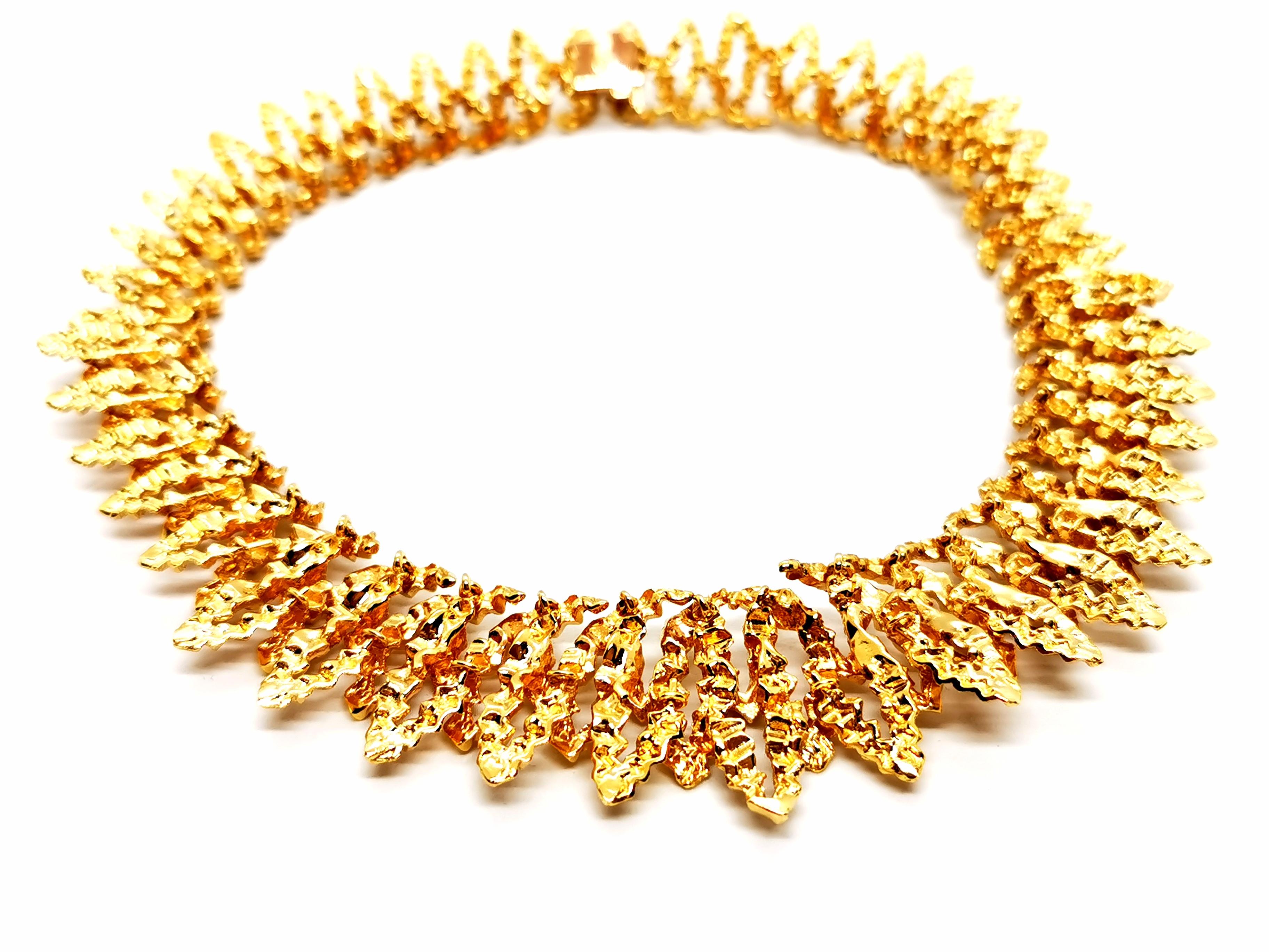 Vintage necklace, signed by Chaumet, in 750 thousandths yellow gold (18 carats), choker model, semi-rigid, in fall, composed of a superposition of pointed patterns, embossed texture, length: 38 cm, width : from 1.89 cm to 2.86 cm, total weight: