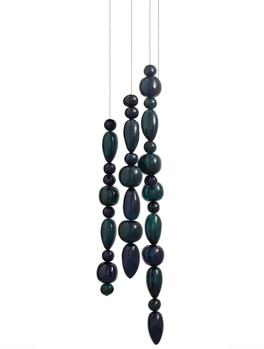 Hand blown glass pendants. 4 glass columns on 42 cm round canopy.
The Chavana collection features pebble inspired glasses stacked along a 17W LED tube, lighting up to form a cascade of light and color. 
The smooth pebbles are filled with glass