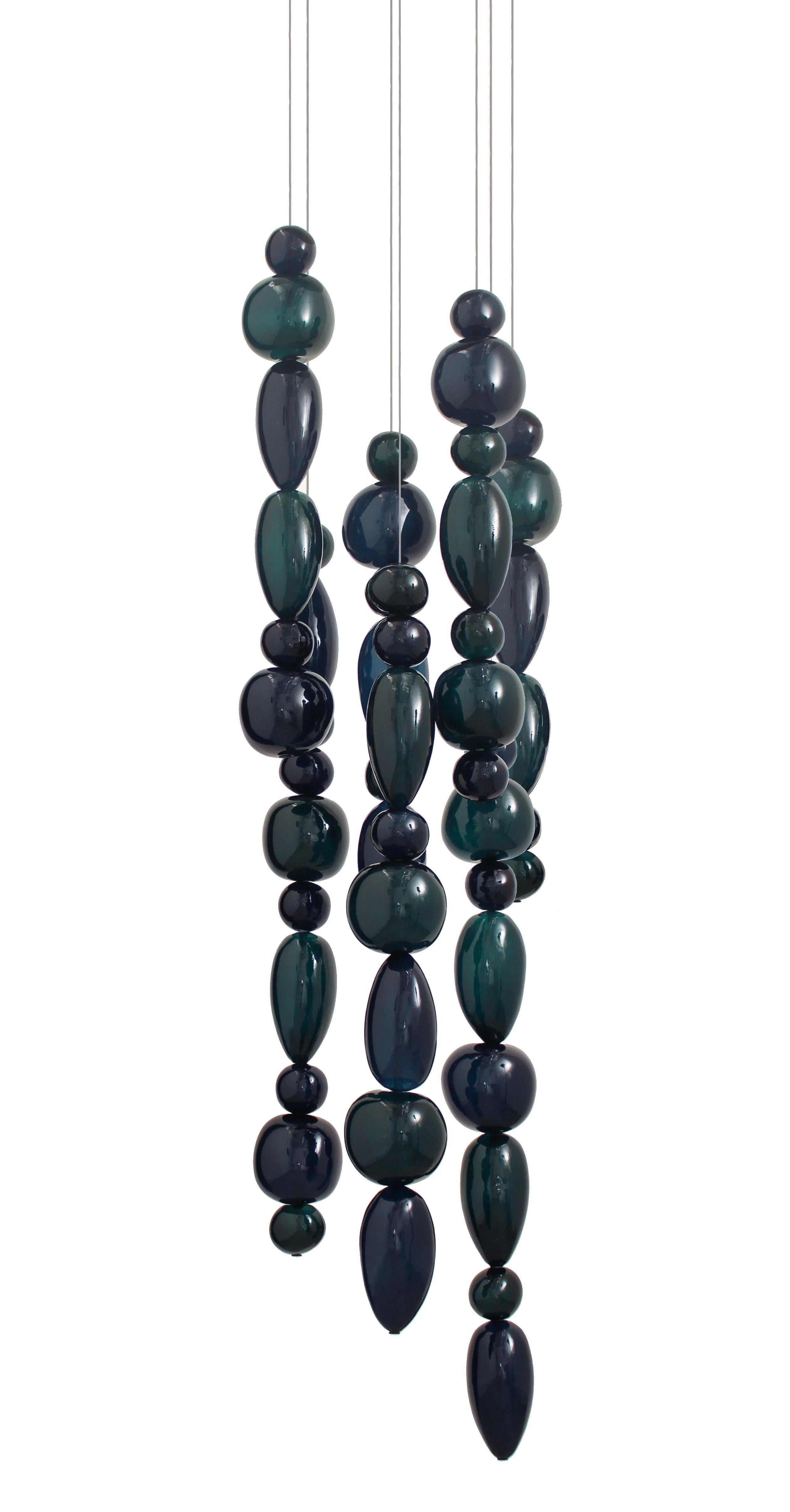 Hand blown glass pendants. 7 glass columns on 42 cm round canopy.
The Chavana collection features pebble inspired glasses stacked along a  17W LED tube, lighting up to form a cascade of light and color.
The smooth pebbles are filled with glass