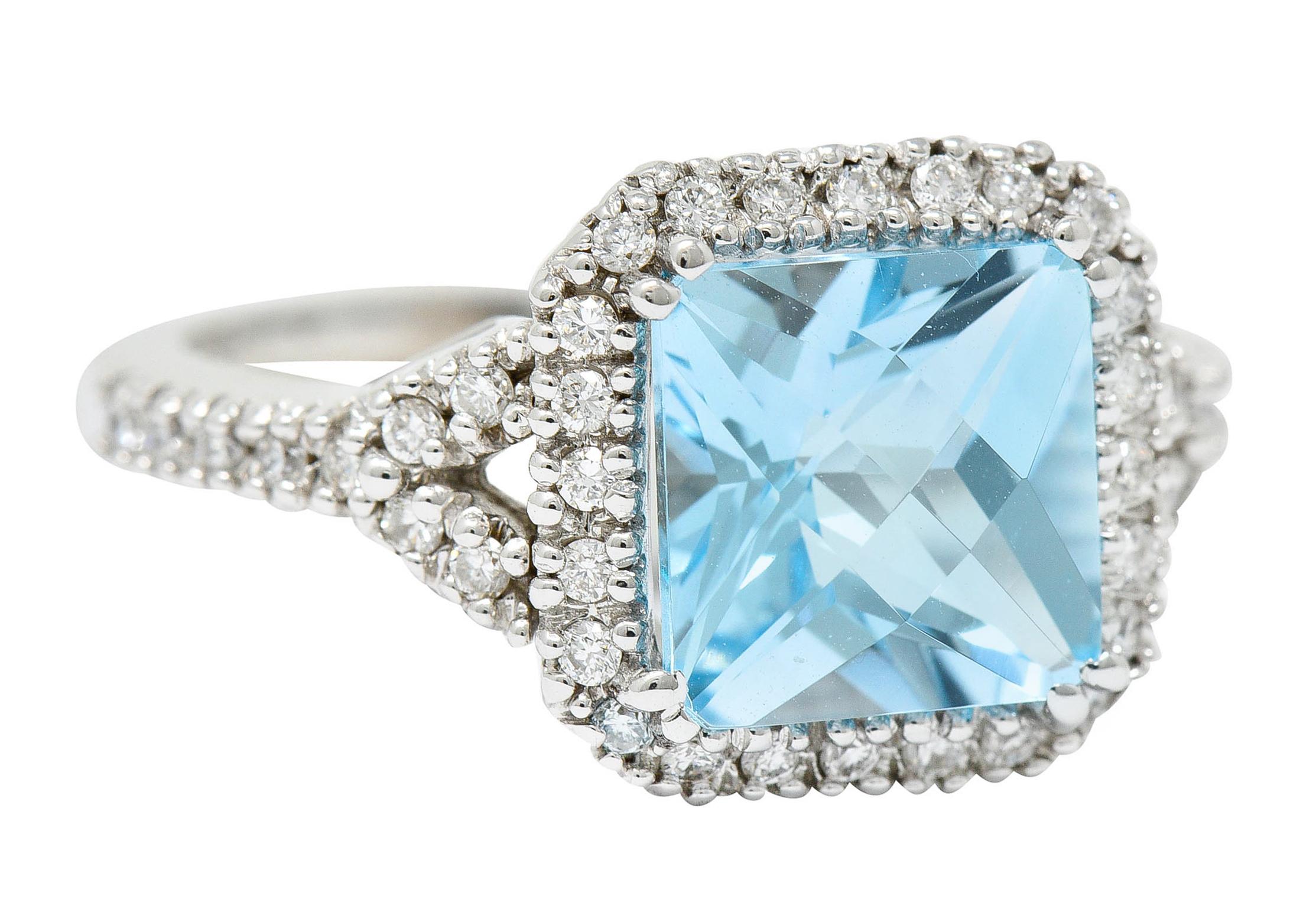 Cluster ring centers a 8.0 mm square checkerboard cut blue topaz

Transparent and grayish blue in color

Surrounded by a diamond halo and flanked by split shoulders - also diamond accented

Round brilliant cut diamonds weigh in total approximately