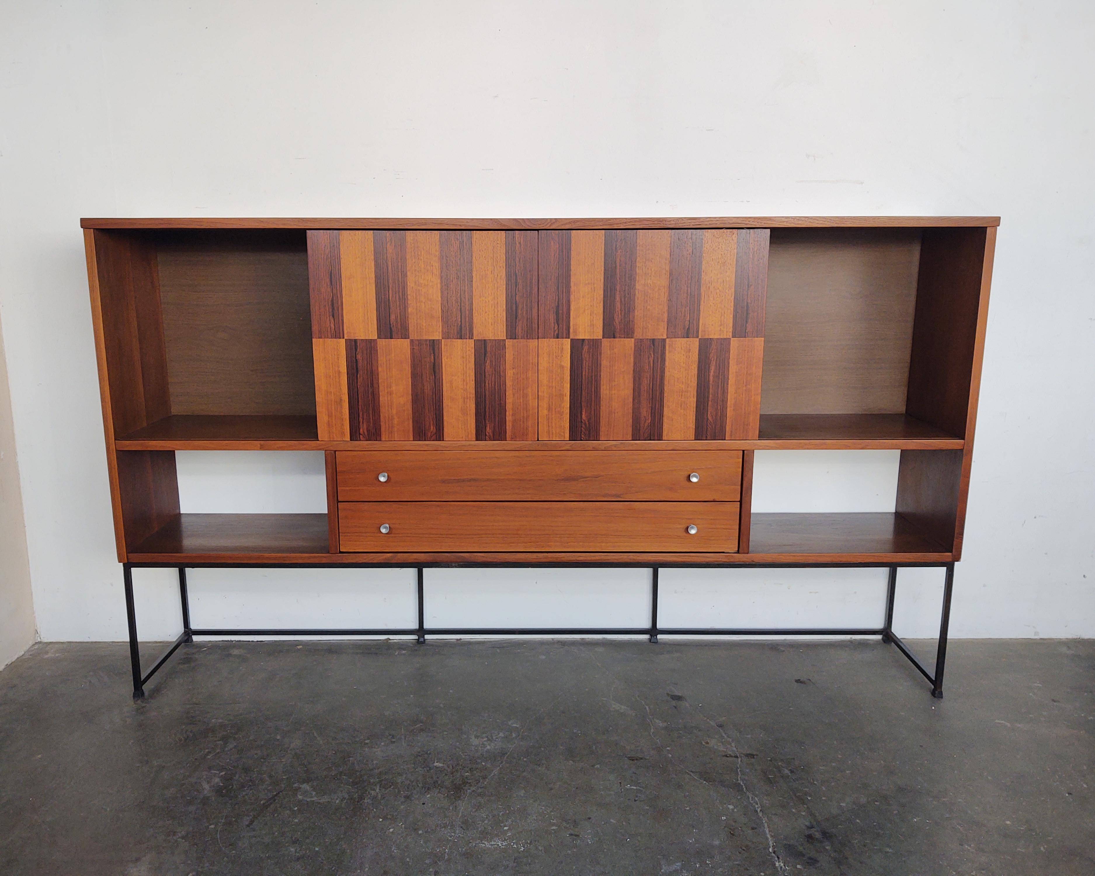 Beautiful cabinet with walnut and rosewood checkered sliding doors and open shelving. Two closed cabinets and two drawers with aluminum hardware. The upper cabinet is mounted on a welded steel frame that has some light patina.

Measures:72