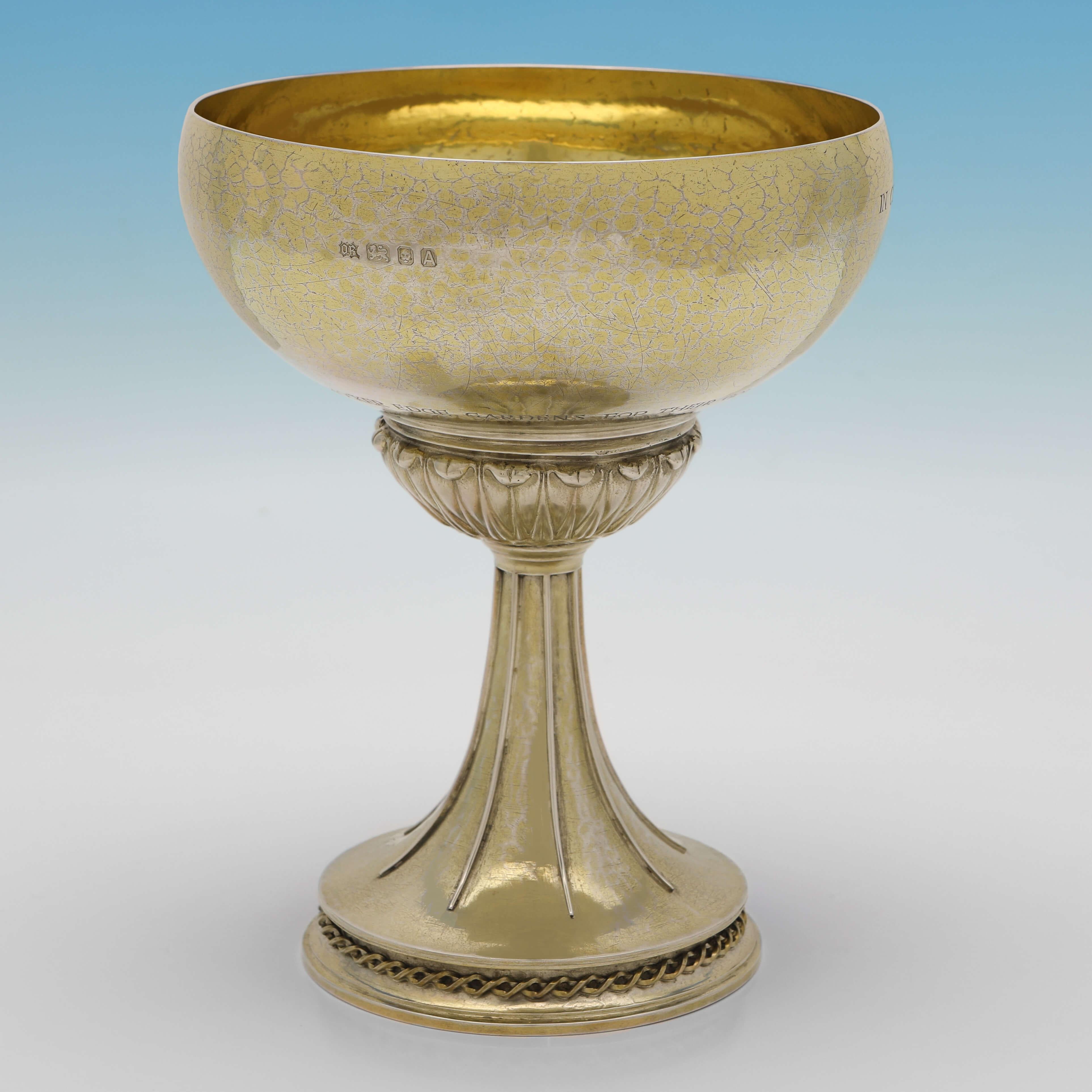 Hallmarked in London in 1936 by Omar Ramsden, this wonderful, Sterling Silver Chalice, is in the Arts & Crafts taste, and features the original gilding and the cast and applied crest of the Royal Horticultural Society. 

The chalice was given as a