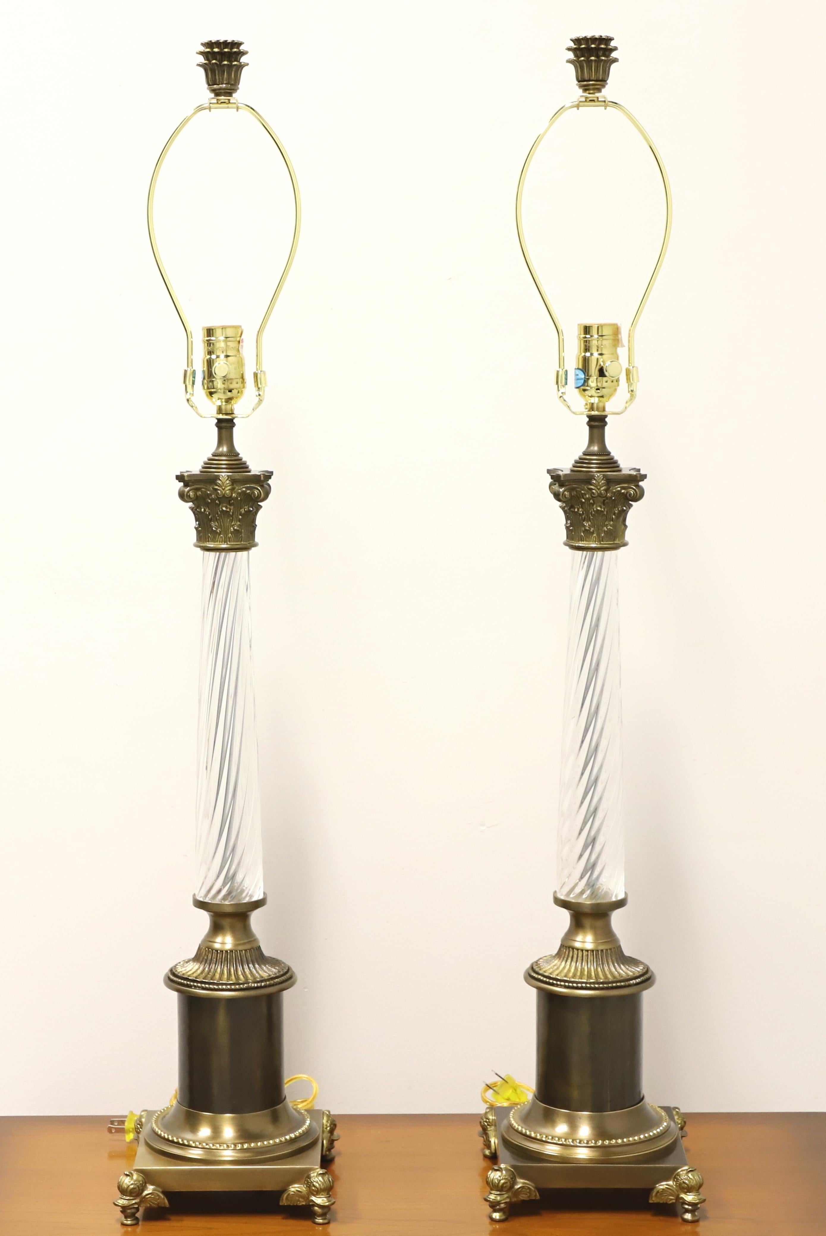 A pair of Traditional style table lamps by Chelsea House. Made of solid brass in the shape of a Ionic column with a swirled glass surround and a solid base with duck head feet at the four corners. Each has a metal harp and decorative brass finial.