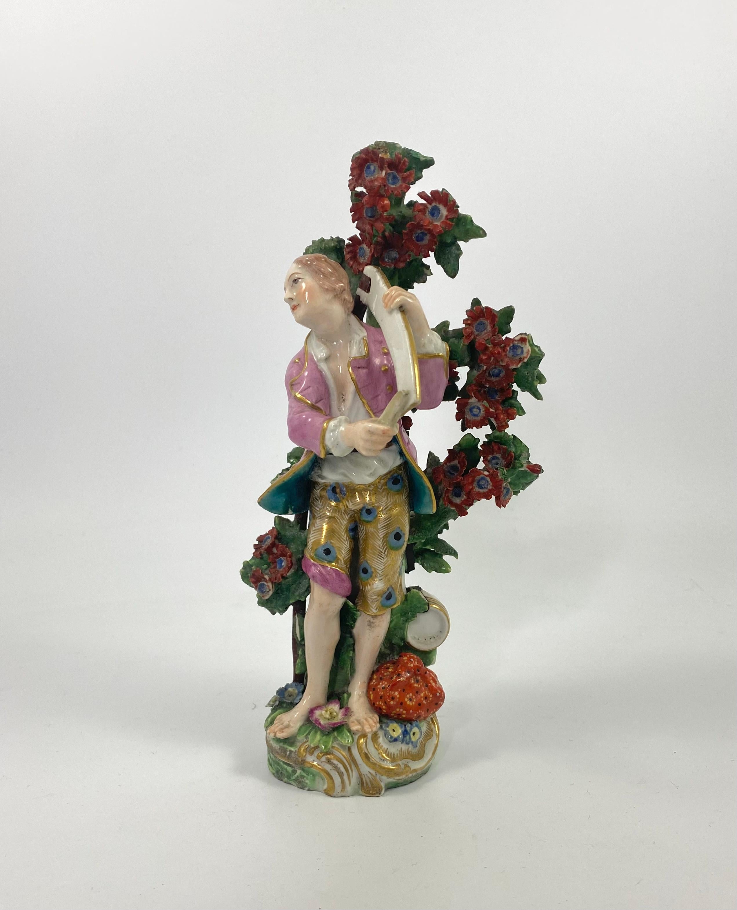 Rare Chelsea porcelain figure, c. 1760. Modelled as a Farmer, wearing 18th Century costume, of a pink jacket and breeches elaborately painted with peacock feathers, whilst carrying a large scythe. He stands before a flowering tree, upon which rests