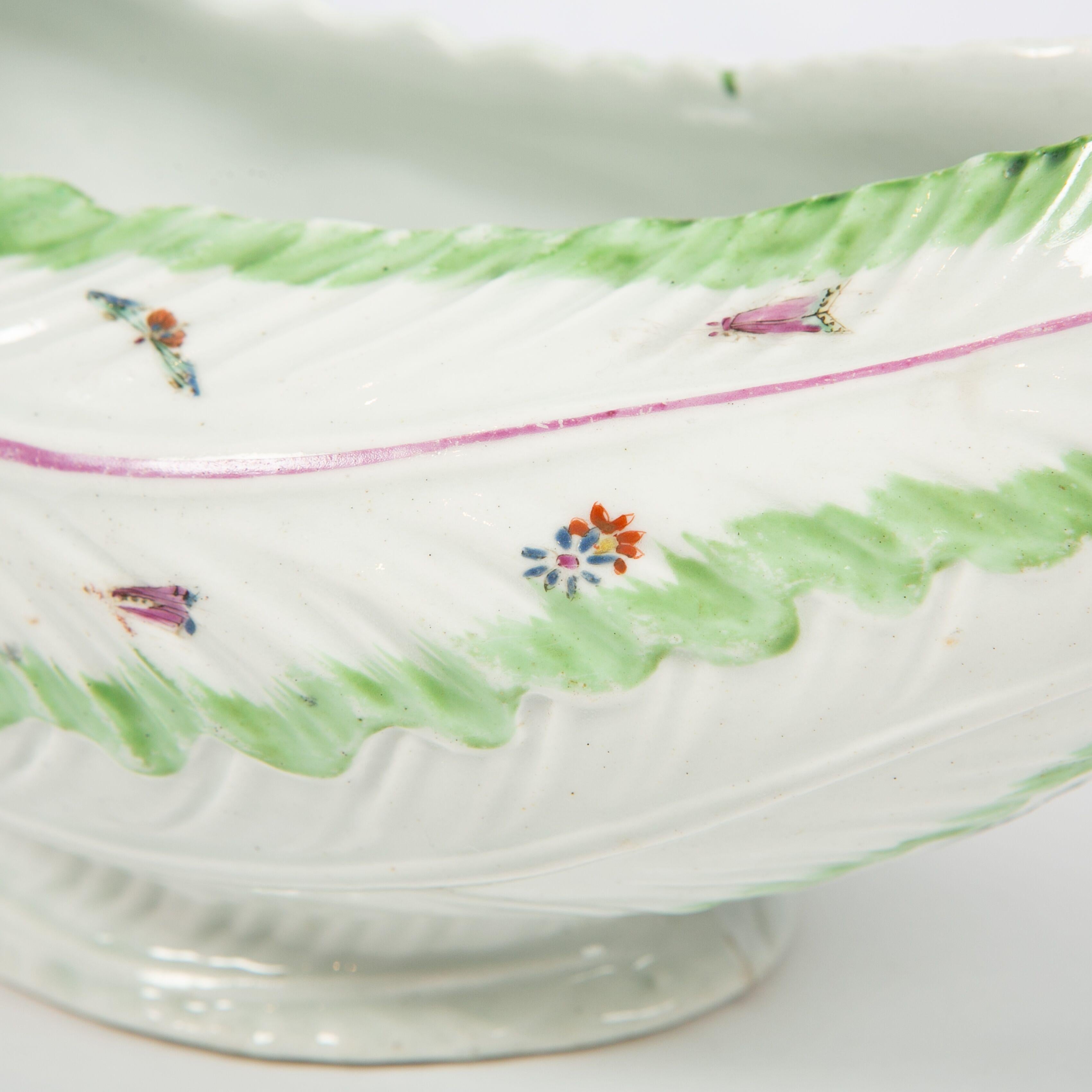  This sauceboat is beautifully shaped and hand-painted with a light green lettuce leaf pattern on its rim, small painted butterflies, sprigs of flowers, and a stock handle.
The sauceboat is unmarked, as were many early Worcester pieces.
Dimensions: