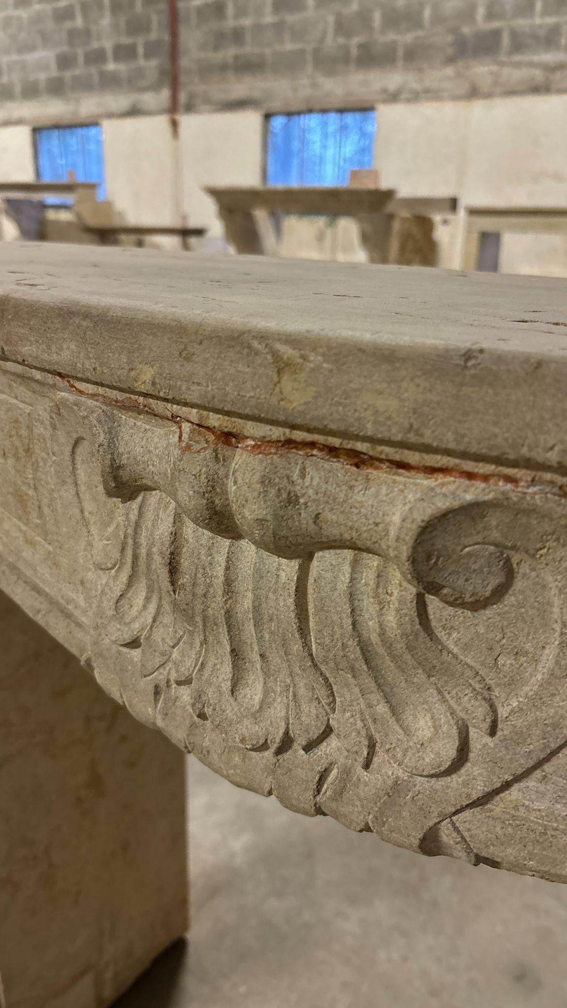 Elegant and full of charm, this antique Louis XV fireplace was hand-carved from natural stone and dates back to the 18th or early 19th century. Its graceful lines, soft curves, and classic proportions are typical of the French Rococo style, with