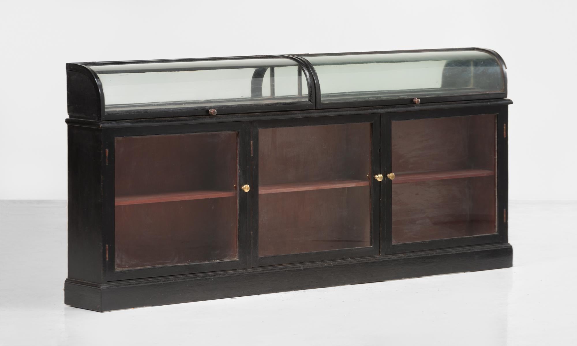 Chemist shop counter, England, circa 1930.

Ebonized wood case with painted interior, brass hardware and curved glass top.