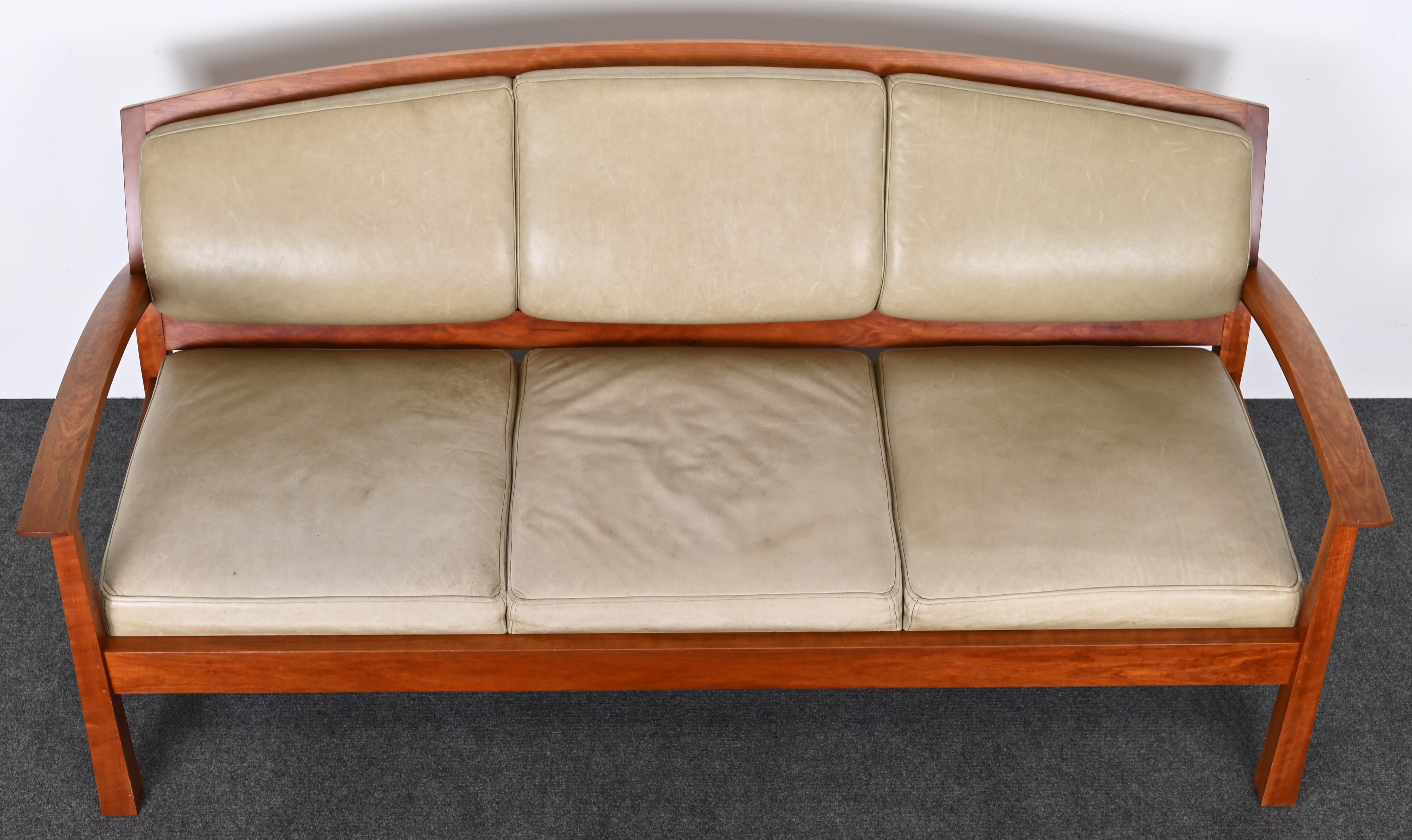 A handmade cherry sofa or settee designed by Thomas Moser and hand-crafted in his studio. Details show pegs and craftsmanship throughout and the woodwork is in very good condition as shown in the images. The leather cushions do show some years of