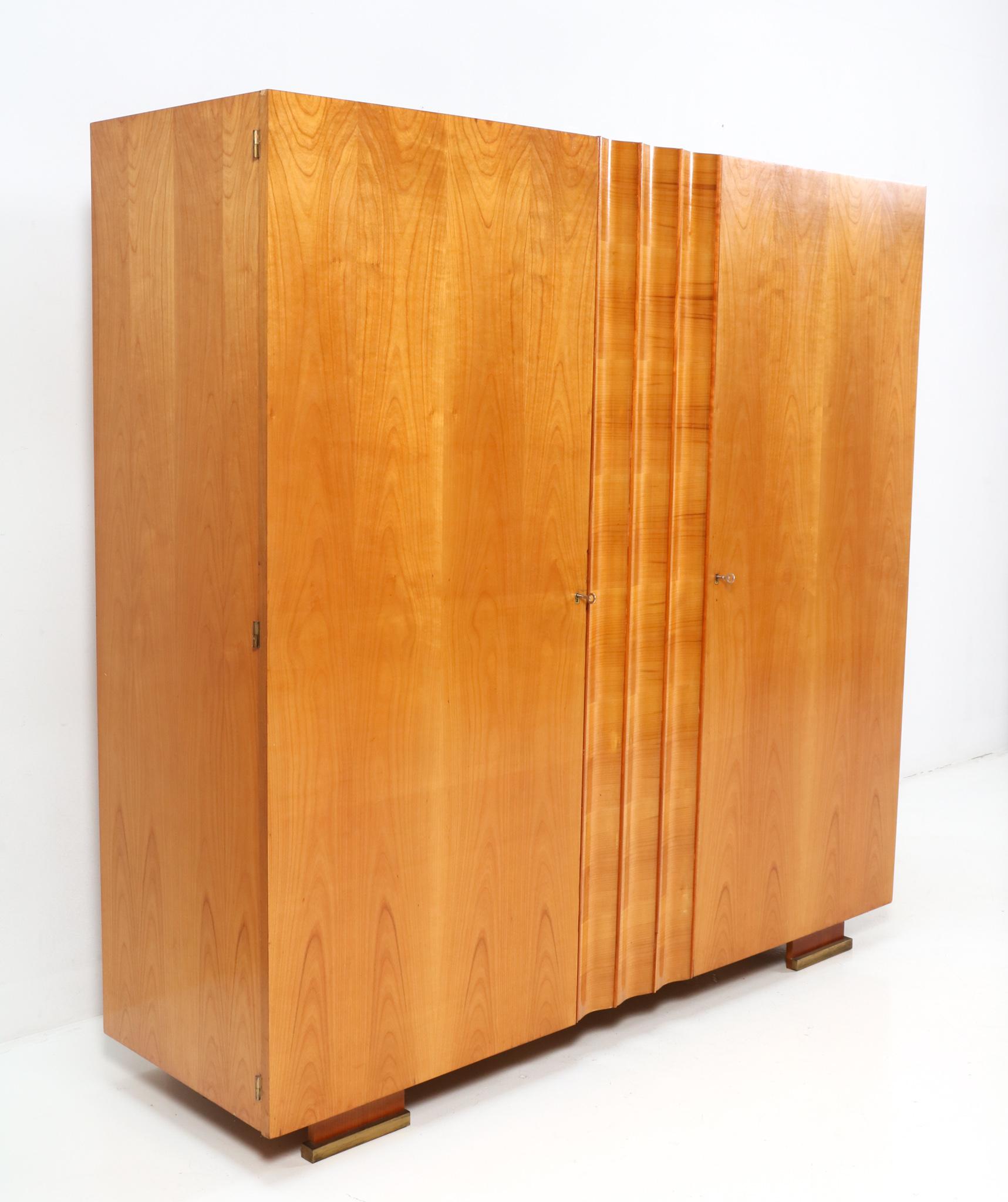 Magnificent and rare Art Deco armoire or wardrobe.
Design by De Coene Frères Kortrijk.
Striking Belgium design from the 1930s.
Solid cherry and original cherry veneer with brass details at the front feet.
Behind the left door with the original