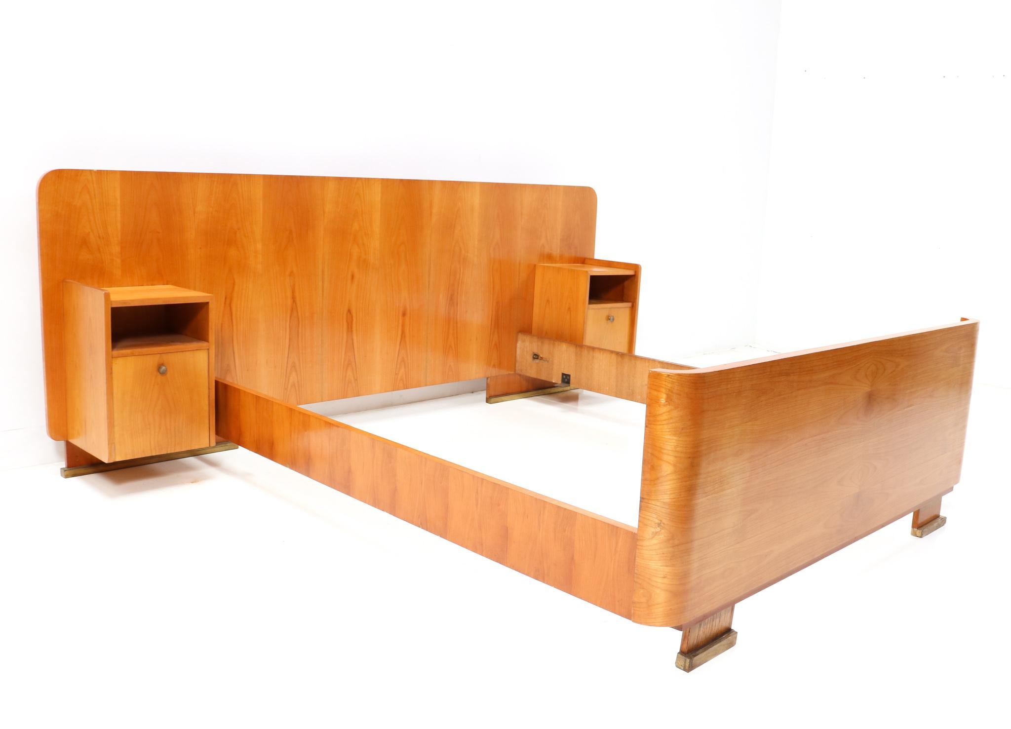 Magnificent and rare Art Deco bed frame with two original integrated nightstands or bedside tables.
Design by De Coene Frères Kortrijk.
Striking Belgium design from the 1930s.
Solid cherry and original cherry veneer with brass feet.
This