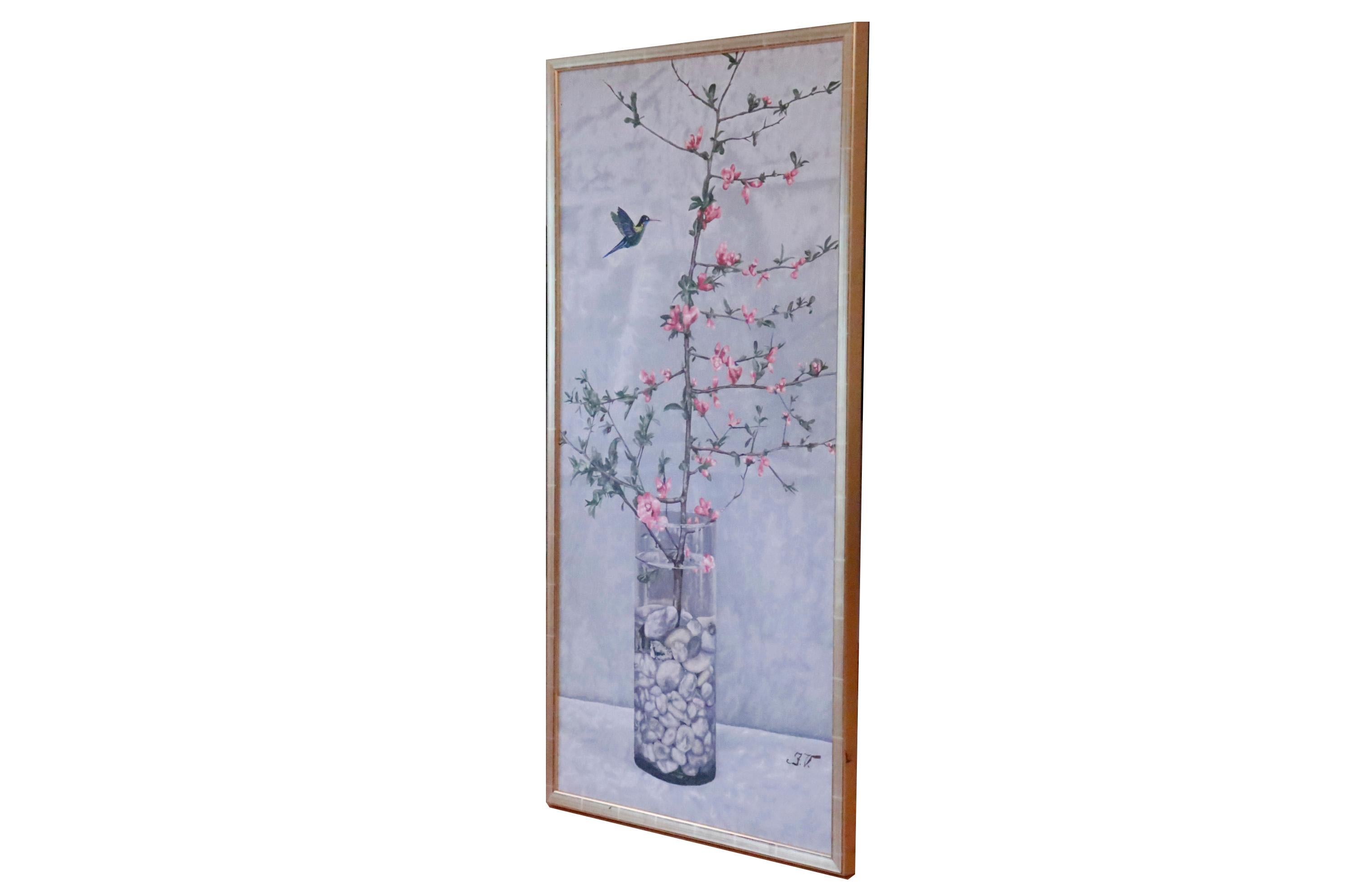 A contemporary acrylic on canvas. A cherry blossom branch in a tall vase filled with pebbles is set against a gray background. A hummingbird mid flight can be seen to the left. Initialed by the artist in the lower right corner. Signed and dated in