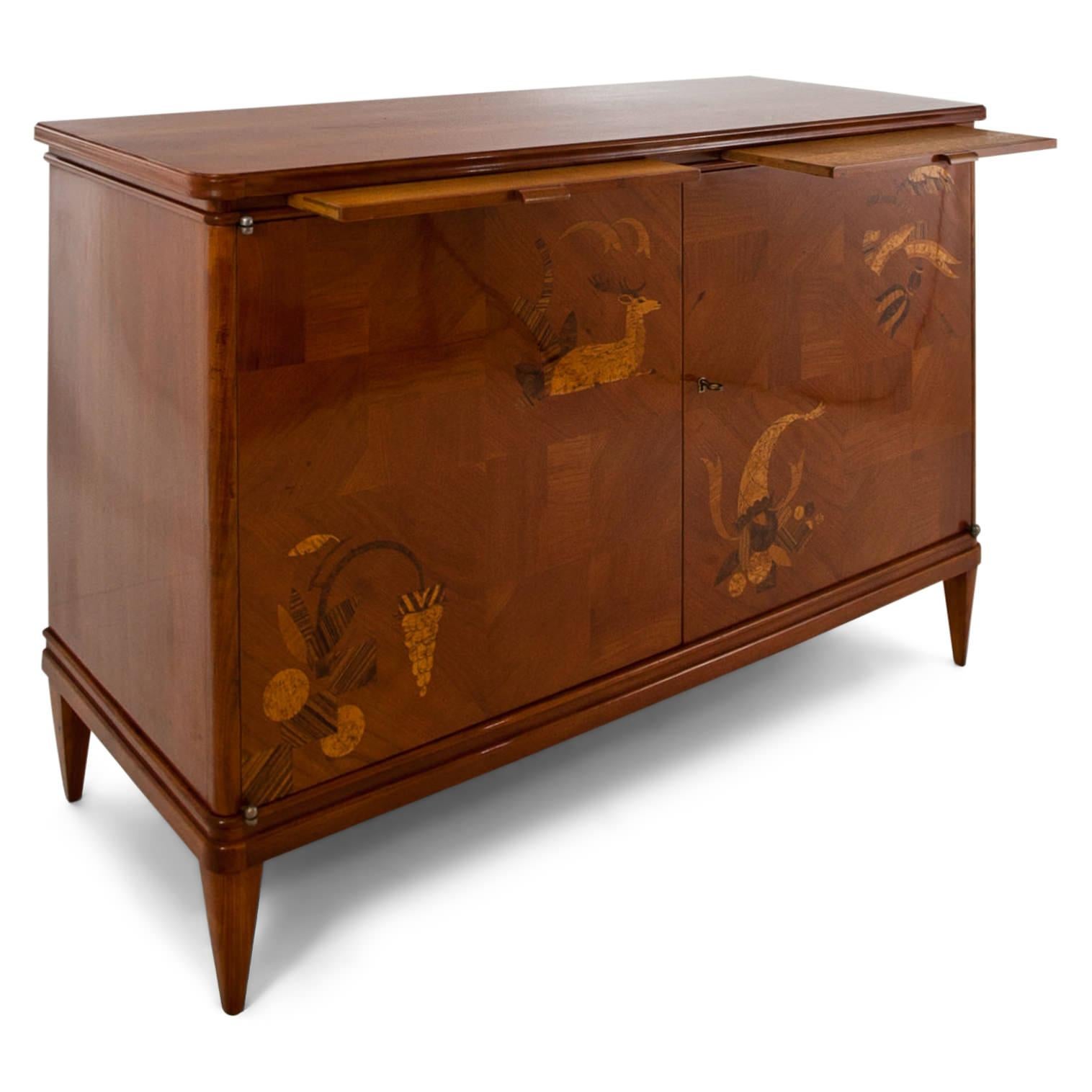 Two-doored cabinet on tapered feet with a parquetry front out of cheerywood and inlays in the shape of plants, vines, a deer and a cornucopia. There are two pullout surfaces directly underneath the top and the interior has one shelf.