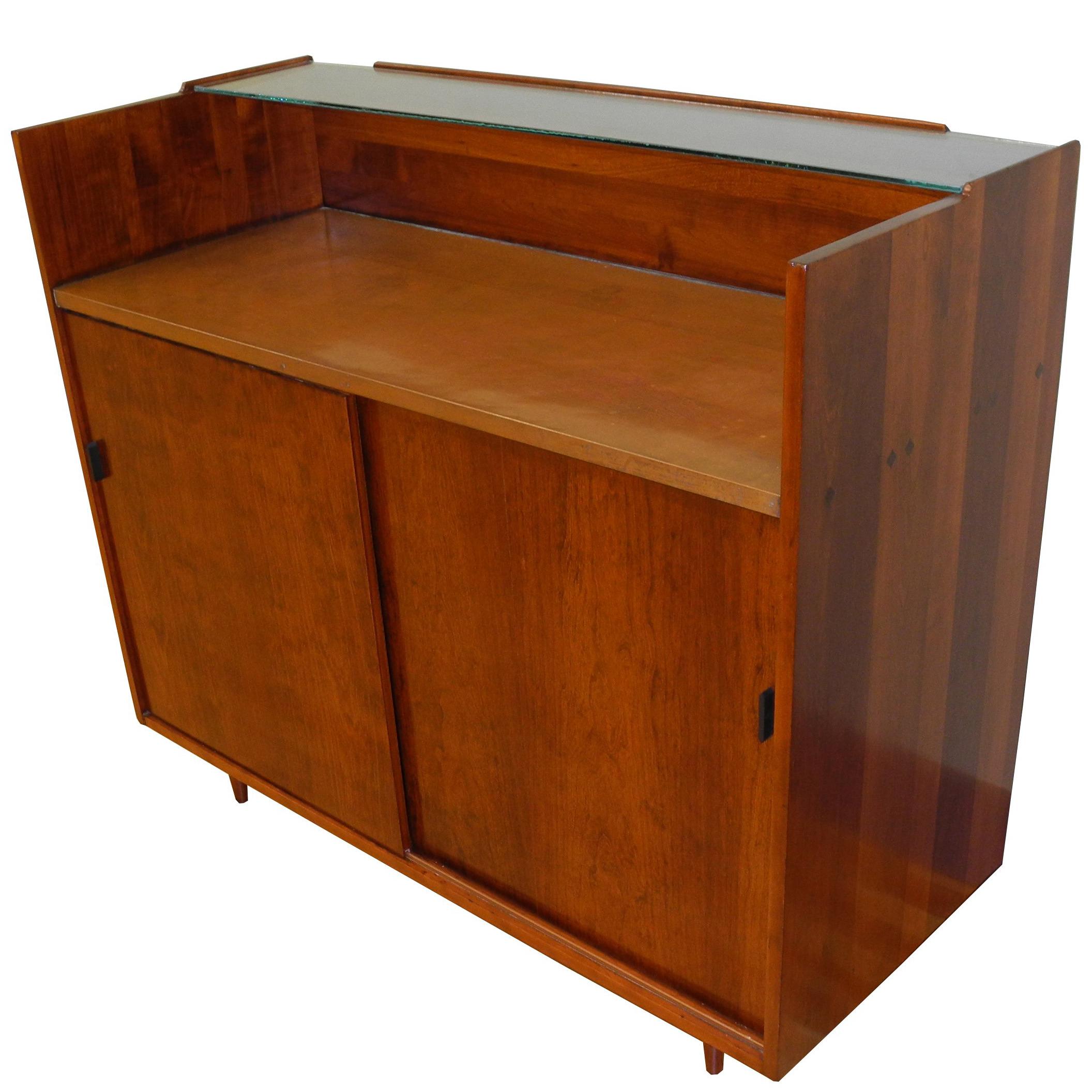 This delightful dry bar is equipped with cabinet space with two drawers and a cut out shelf for bottles. It is made of solid cherry with a copper countertop and glass top shelf. Designed by Kipp Stewart for Glen of California Furniture, 1950s.