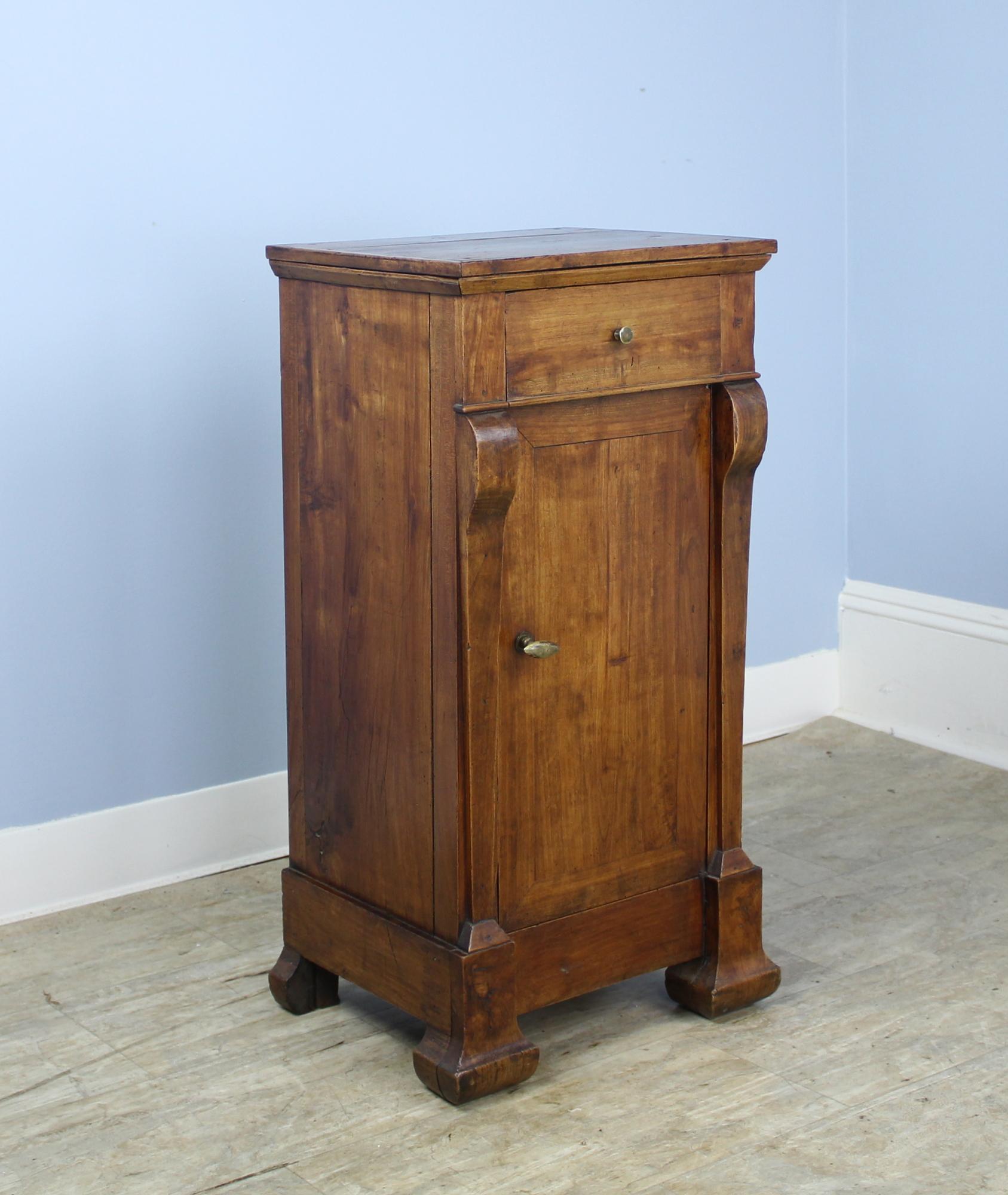 Terrific graining on this cherry side cabinet, with good carved details at the top. Sweet little drawer, and a hand-turned small knob. Lovely classic chamfered feet. Great storage for a practical and handsome nightstand. Correct height for a lamp.