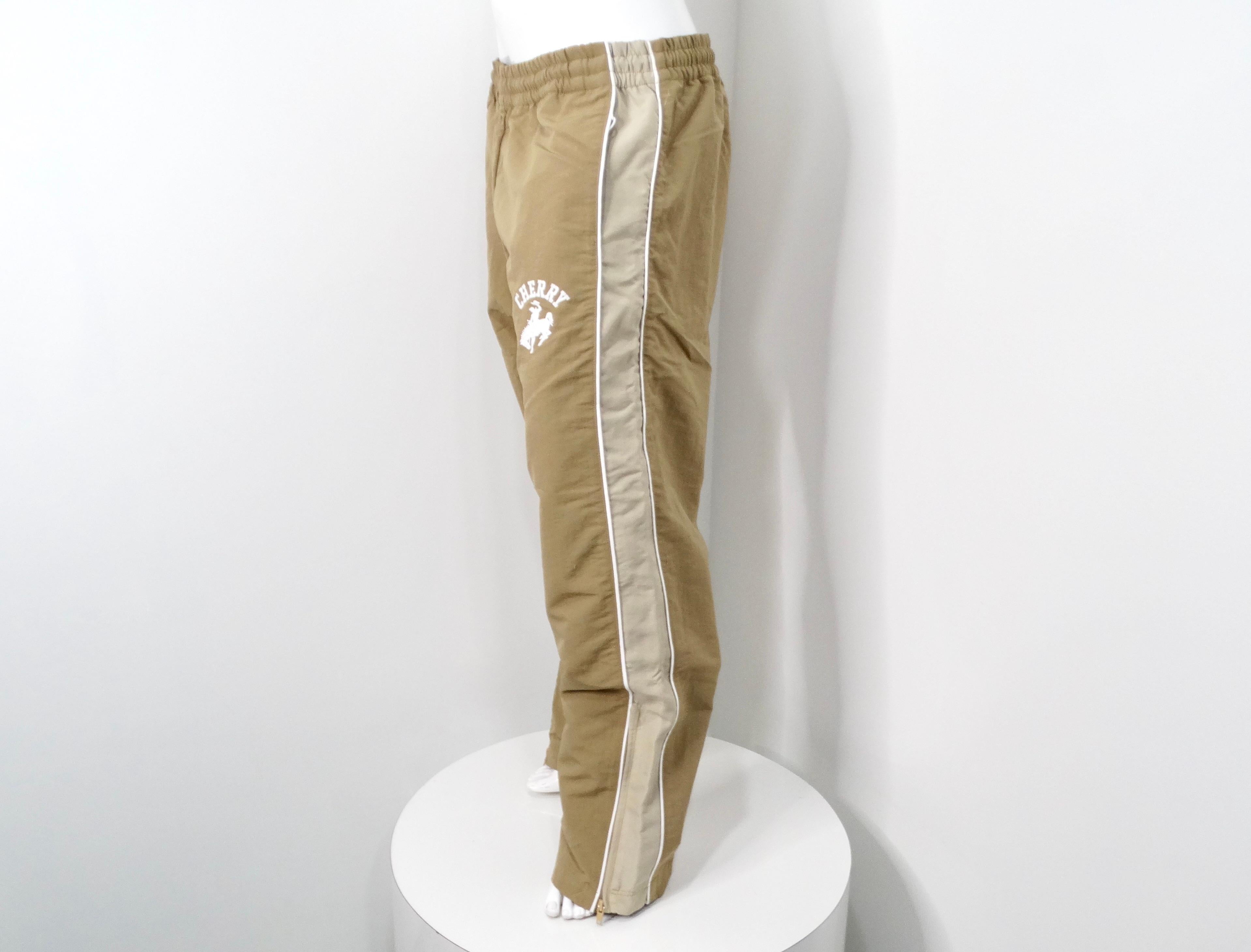 Embrace a fusion of streetwear and Western flair with the Cherry LA Western Khaki Track Pants. These pants are crafted with a durable nylon outer shell and a waterproof coating, ensuring both style and resilience. Distinctive contrast piping and