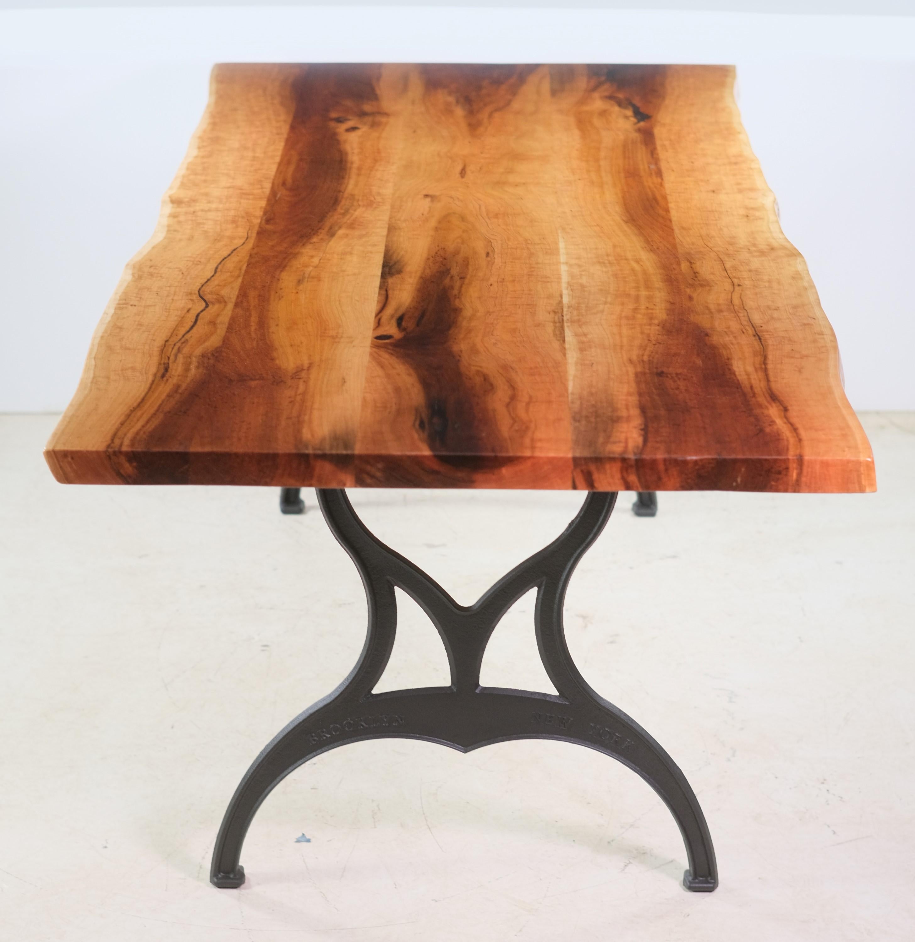Newly made table featuring a double slab live edge cherry top with Brooklyn, New York cast iron legs. Live edges follow the original curves of the tree truck. Resin accent where the tree branched into parts. The slabs have an epoxy base coat and