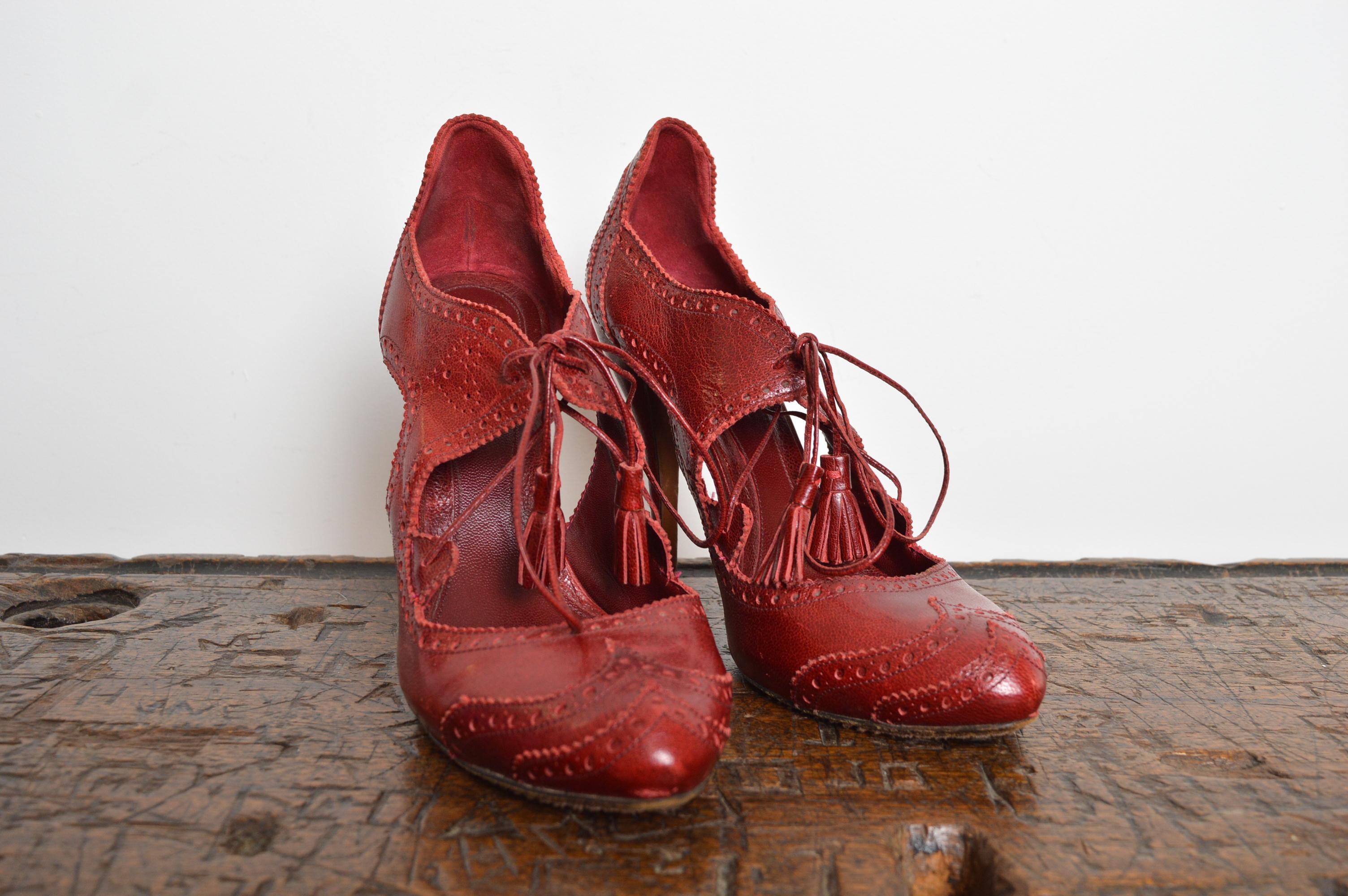 Victorian Inspired Cherry Red lace up peep-hole heels by ALEXANDER McQUEEN featuring tasseled laces, finely perforated decoration and stiletto heels.
Size; UK 6.5 / EU 40
Heel Height; 4.5” (1” Tall at the front of shoe providing a 3.5”