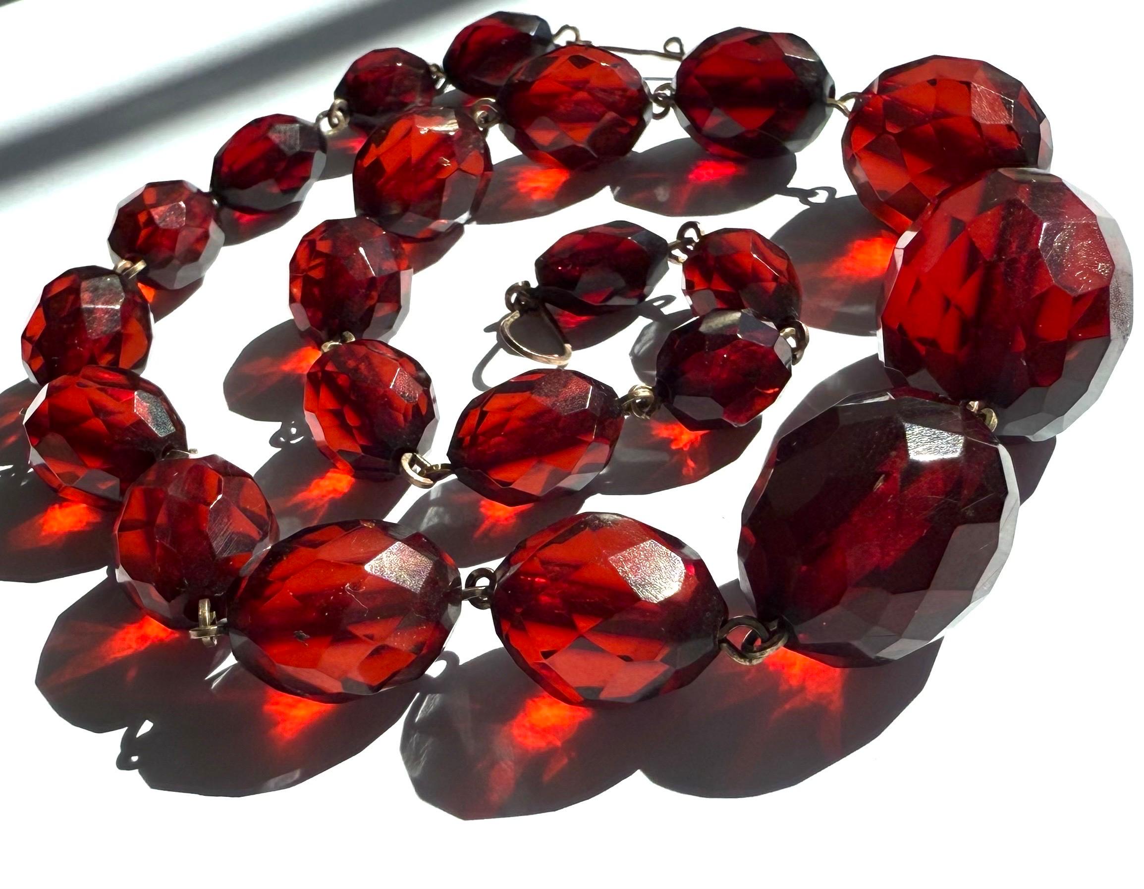 Glamuroso collar Art Decó de baquelita roja cereza facetada, con cuentas graduadas unidas por eslabones metálicos en excelente estado. La baquelita, el primer plástico sintético, fue inventada en 1907 por Leo Baekeland. Este plástico