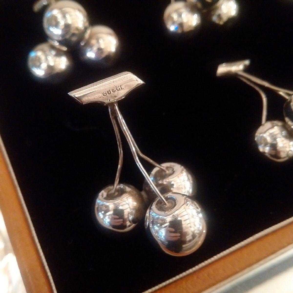 A set of six Sterling silver place-card or menu holders in the form of three cherries with stalks, each holder bearing Gucci hallmarks to the stems, upon which the cards rest. Gucci produced a range of figurative design menu holders in the 1960s,